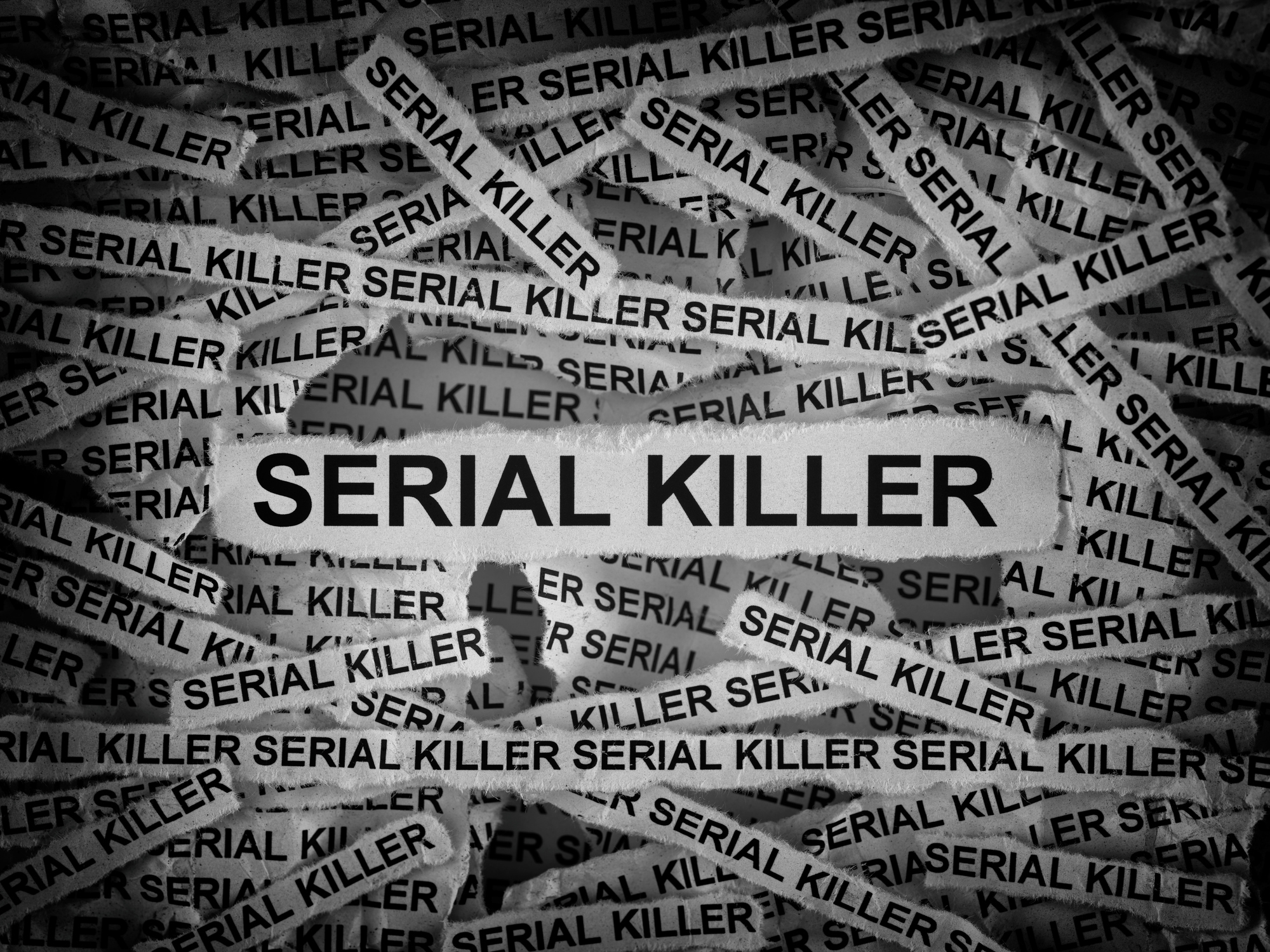 Strips of newspaper with the words Serial Killer typed on them. Black and white. Close up.
