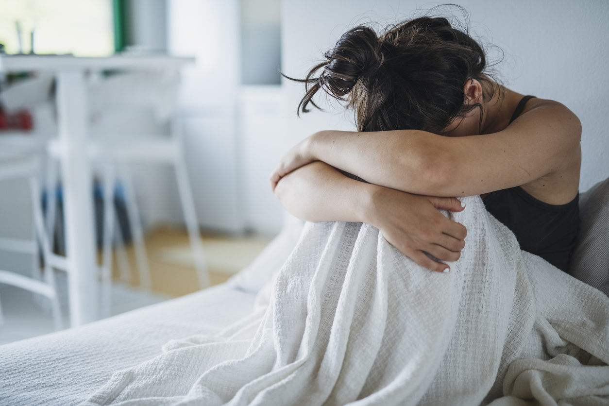Young woman laying in bed at home struggling with mental breakdown.