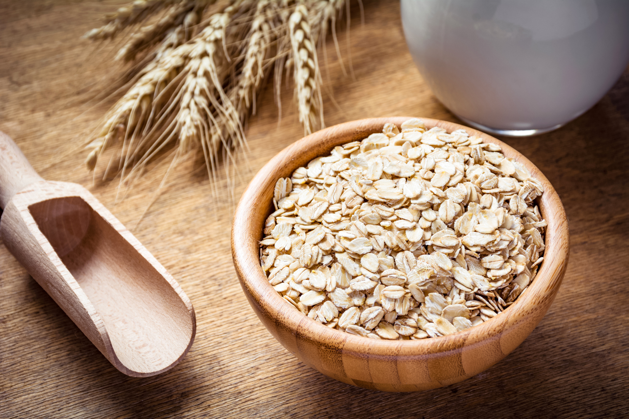 Rolled oats (oat flakes), milk and golden wheat ears on wooden background. Raw food ingredients, healthy lifestyle, cooking food