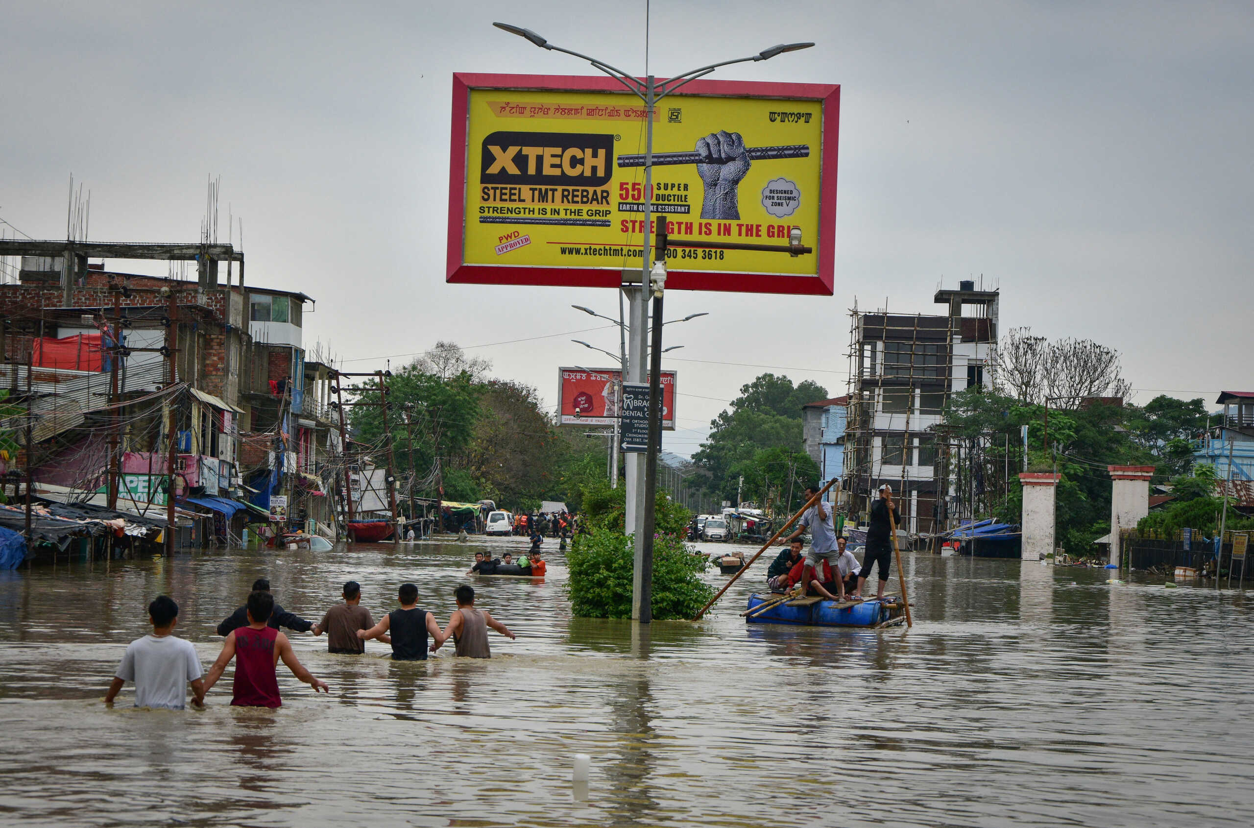 People use a makeshift raft and others wade through flooded road to reach a safer place after heavy rains caused by Cyclone Remal in Imphal, Manipur, India, May 29, 2024. REUTERS