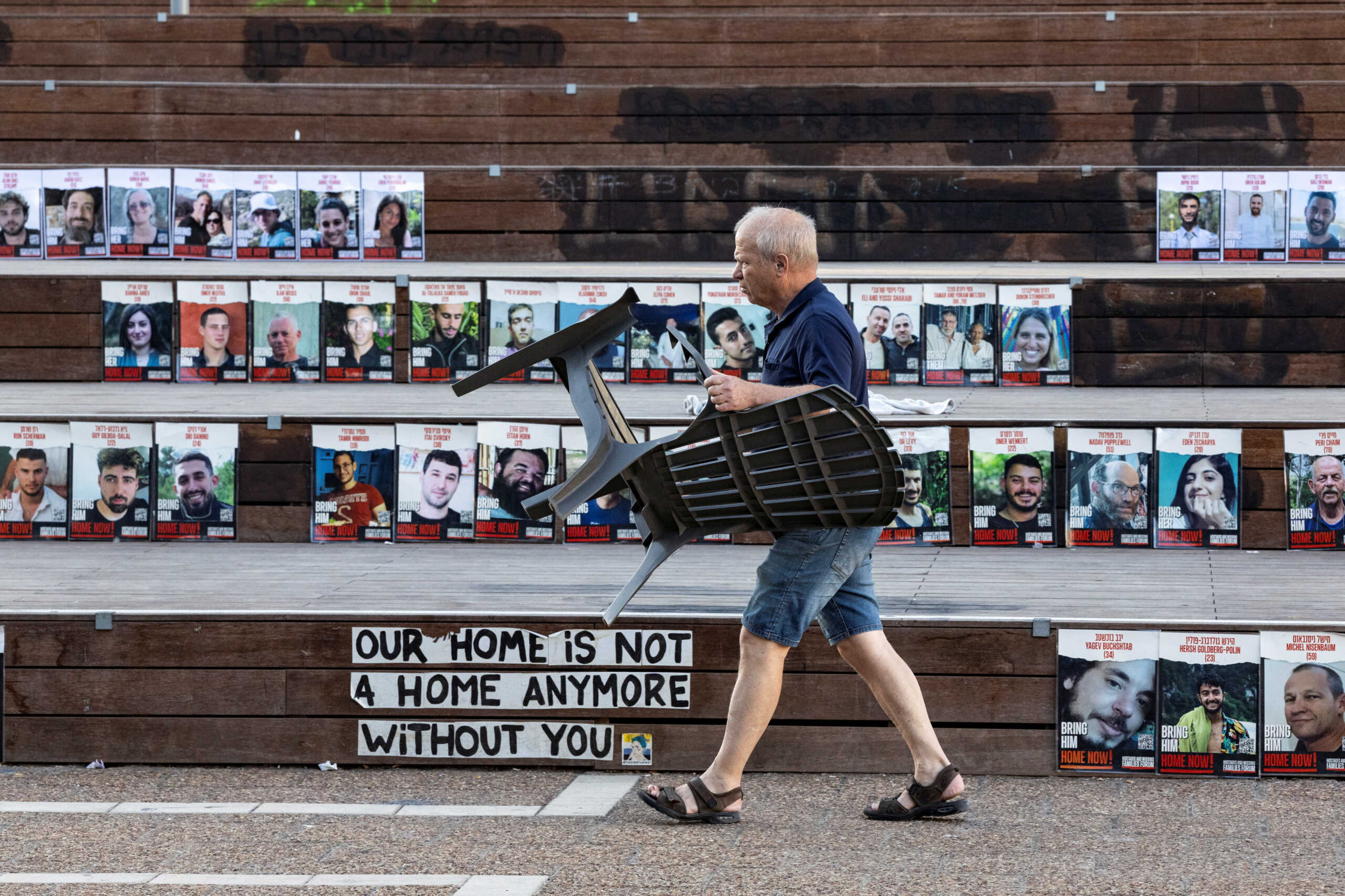 A man carrying a chair walks past pictures of the hostages kidnapped during the deadly October 7 attack by the Palestinian Islamist group Hamas from Gaza, in Tel Aviv, Israel, May 31, 2024. REUTERS