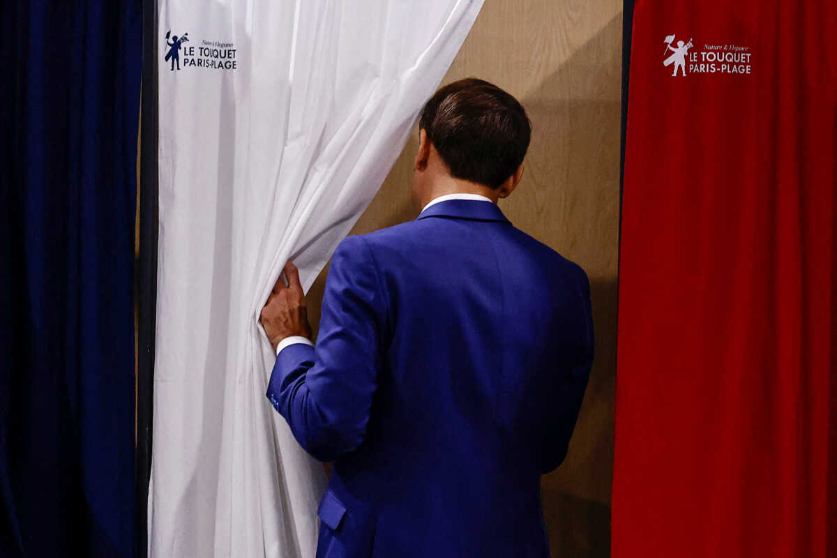 French President Emmanuel Macron enters a voting booth as he visits a polling station to vote during the first round of the early French parliamentary elections, in Le Touquet-Paris-Plage, France, June 30, 2024. REUTERS