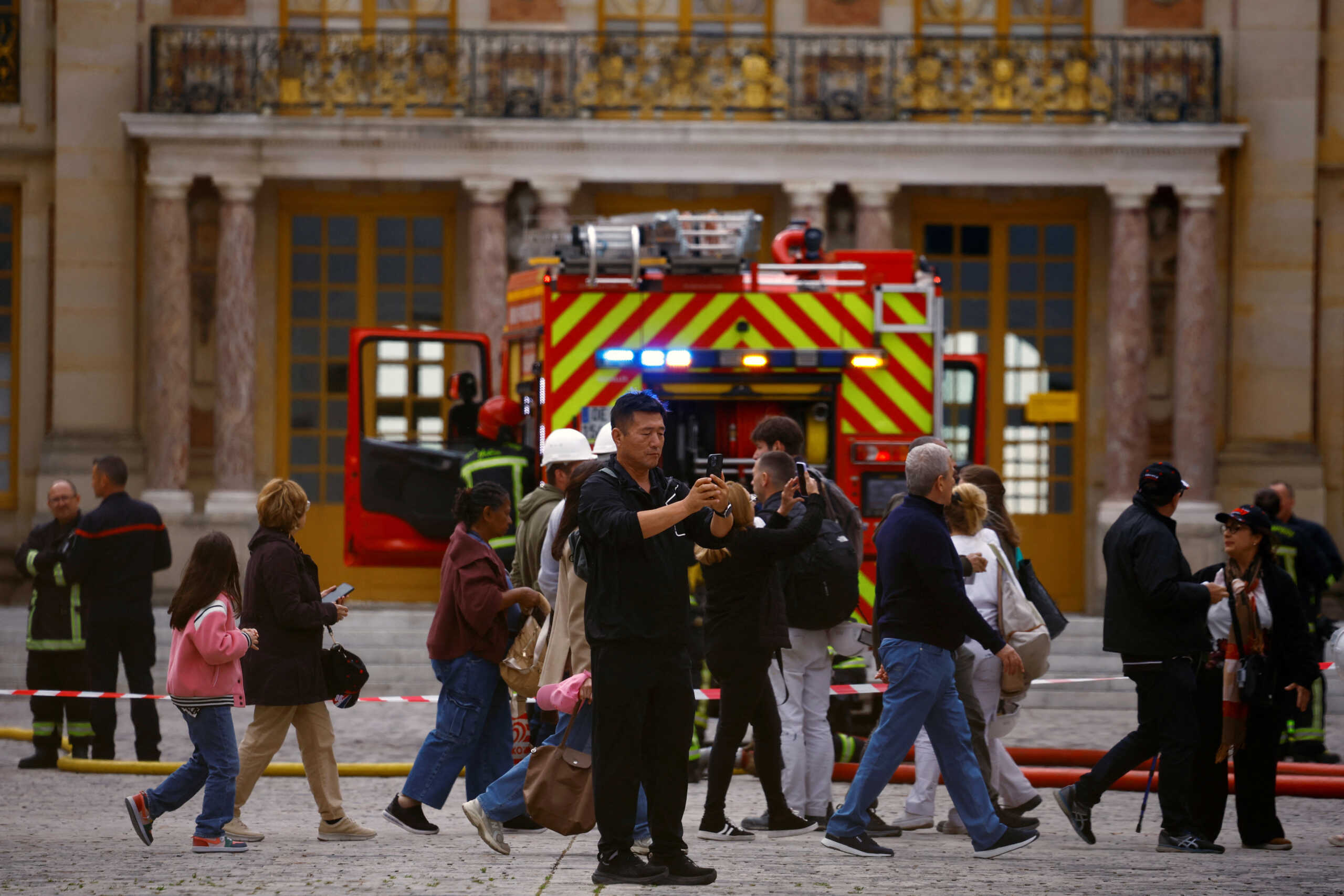 Visitors take pictures as French firefighters work after a fire broke out at the Chateau de Versailles forcing the site's evacuation, but was swiftly brought under control, in Versailles, near Paris, France, June 11, 2024. REUTERS