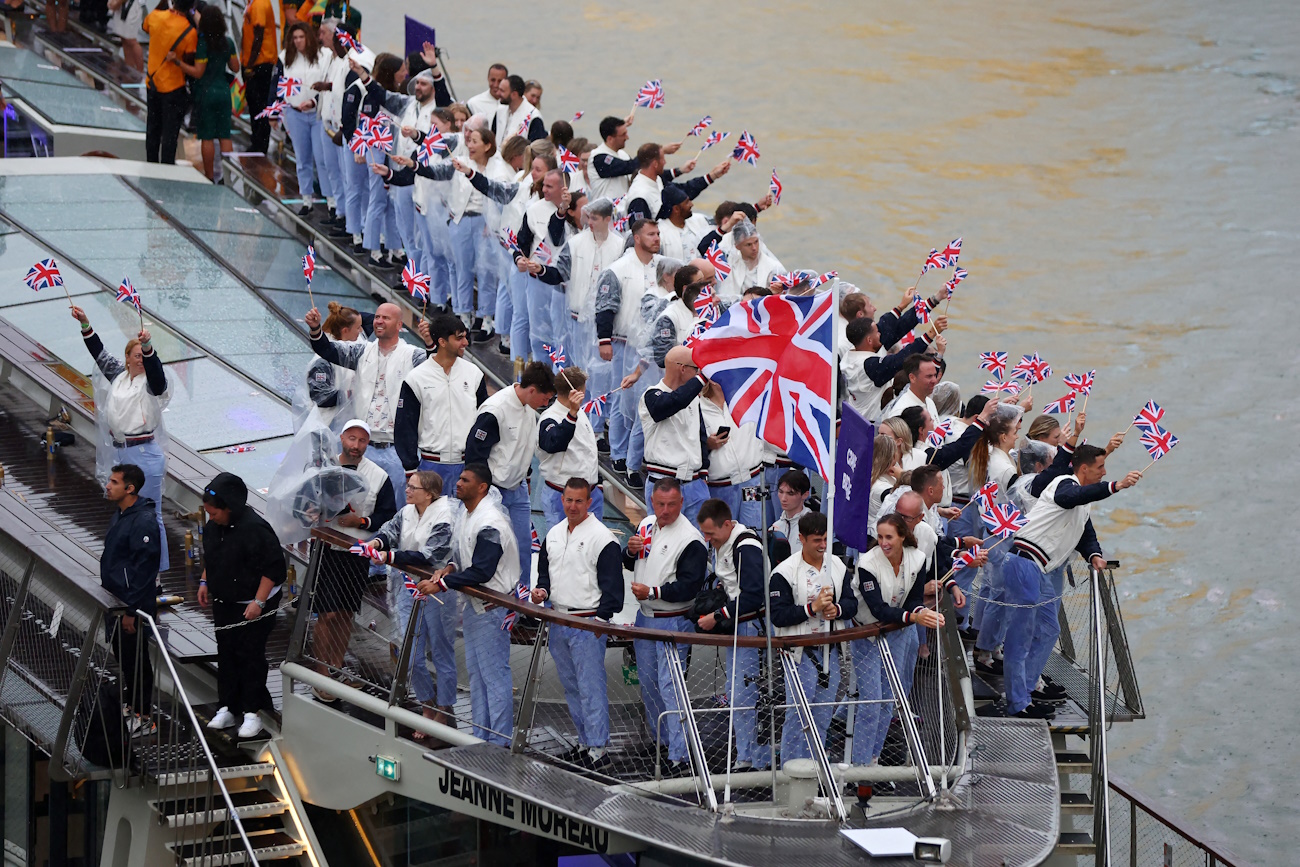 Paris 2024 Olympics - Opening Ceremony - Paris, France - July 26, 2024. Flagbearers Thomas Daley and Helen Glover, of Britain, wave the flag on the athletes' parade team boat along the River Seine during the opening ceremony of the Olympic Games Paris 2024.     Maddie Meyer