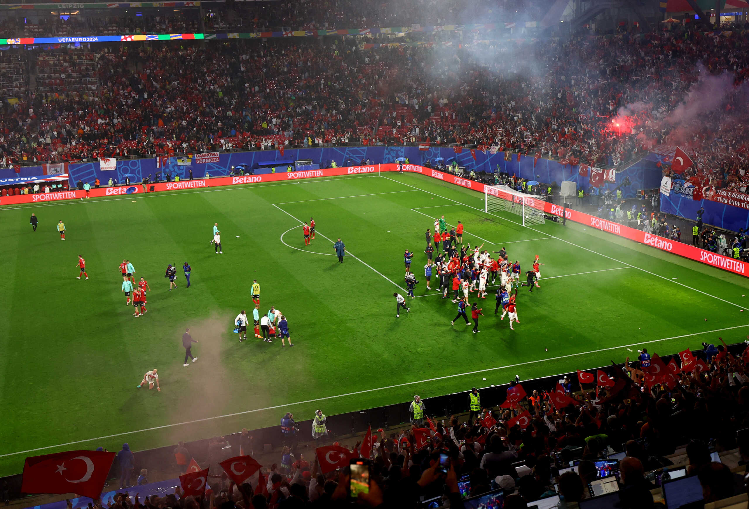 Soccer Football - Euro 2024 - Round of 16 - Austria v Turkey - Leipzig Stadium, Leipzig, Germany - July 2, 2024 Turkey players celebrate after the match as fans set off flares in the stand REUTERS