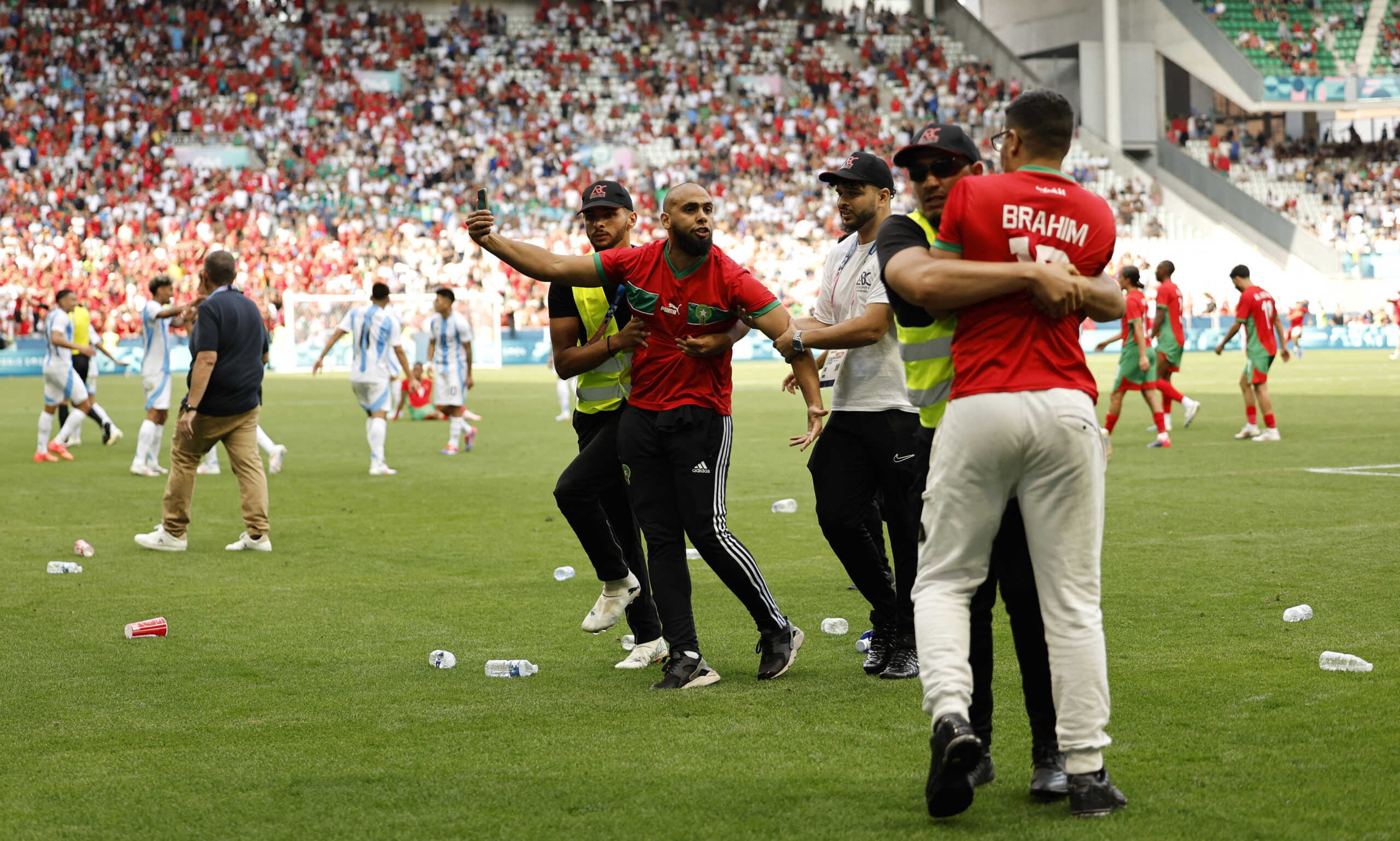 Paris 2024 Olympics - Football - Men's Group B - Argentina vs Morocco - Geoffroy-Guichard Stadium, Saint-Etienne, France - July 24, 2024. Pitch invaders are detained by stewards after the match. REUTERS