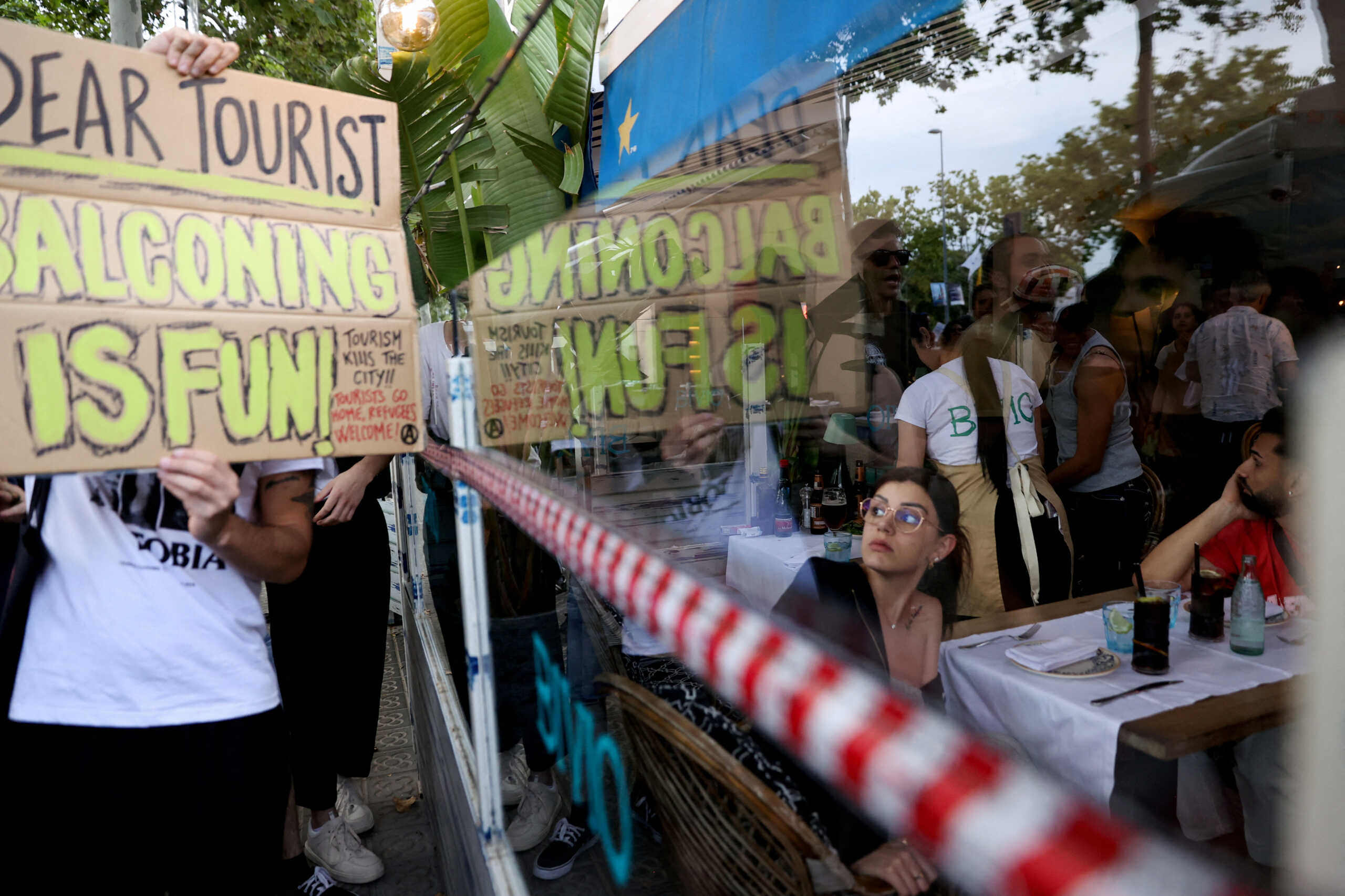 A tourist watches as demonstrators protest against mass tourism in Barcelona, Spain, July 6, 2024. The Catalan capital received more than 12 million tourists in 2023 and expects more in 2024. REUTERS