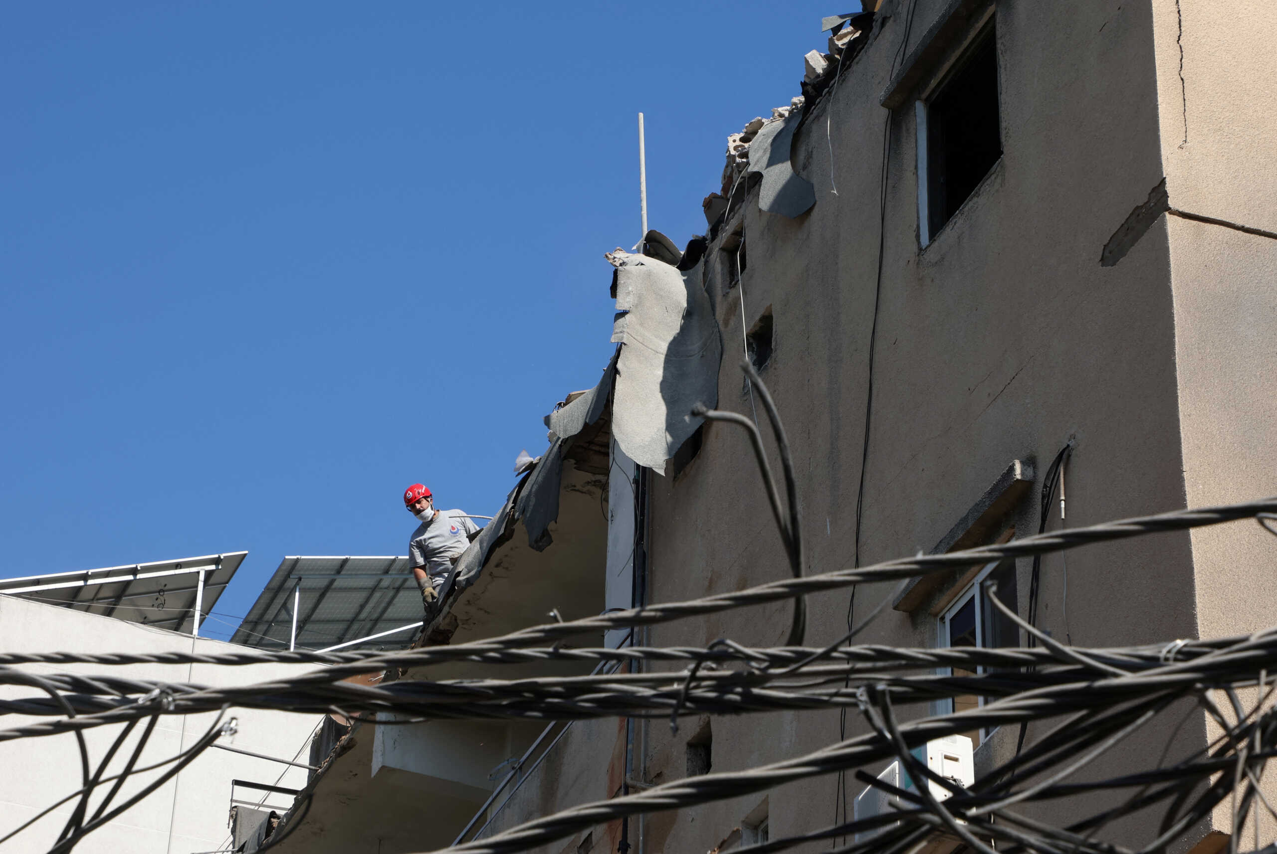 A Hezbollah affiliated civil defence member stands atop a damaged building, the day after an Israeli strike, in Beirut's southern suburbs, Lebanon July 31, 2024. REUTERS