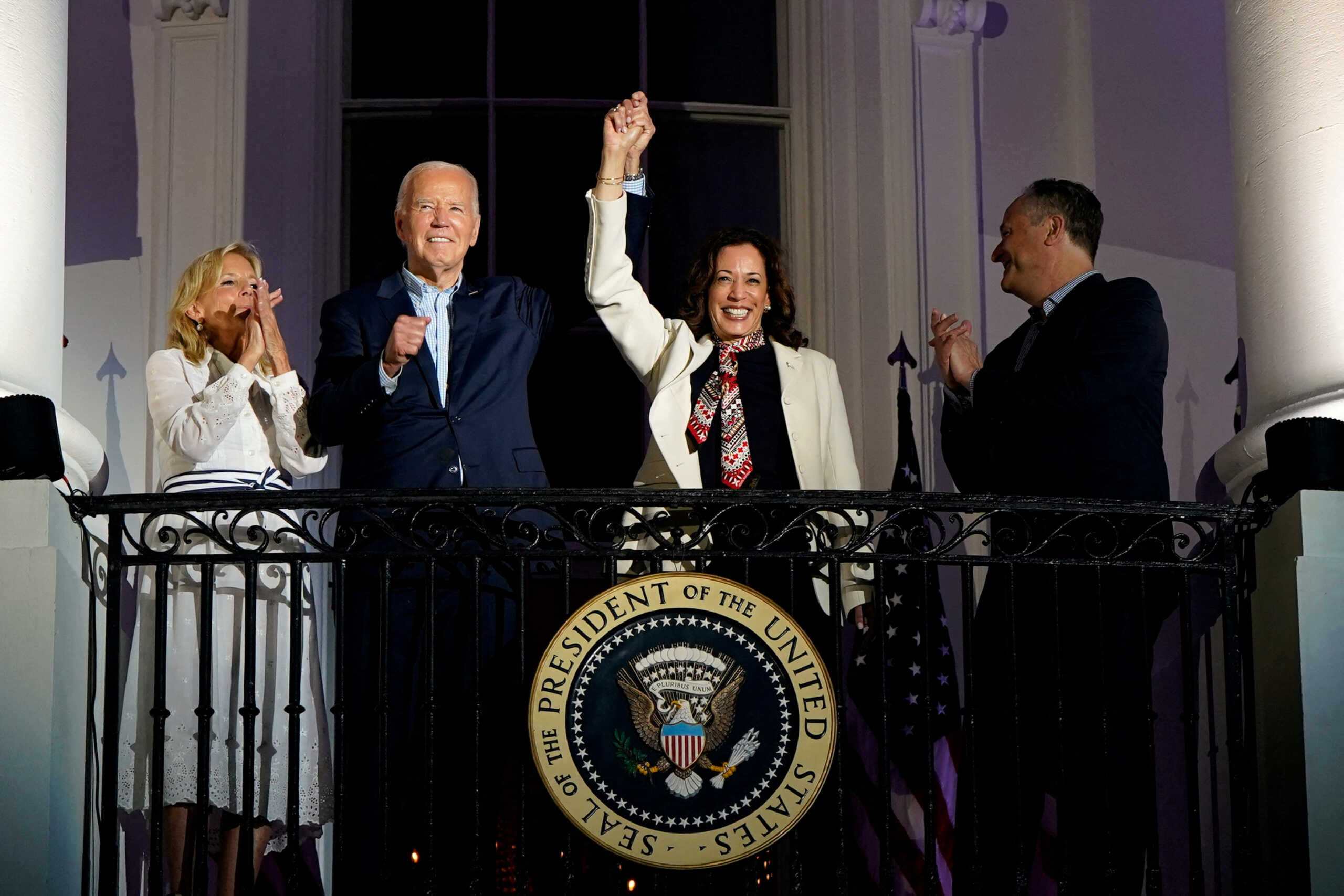 FILE PHOTO: U.S. President Joe Biden and Vice President Kamala Harris raise their hands as they stand on a White House balcony with first lady Jill Biden and second gentleman Doug Emhoff during an Independence Day celebration in Washington, U.S., July 4, 2024. REUTERS