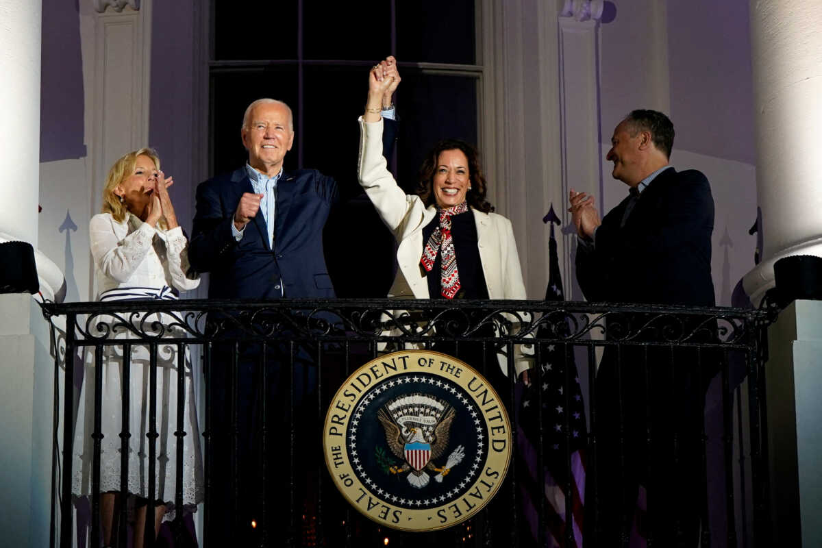 FILE PHOTO: U.S. President Joe Biden and Vice President Kamala Harris raise their hands as they stand on a White House balcony with first lady Jill Biden and second gentleman Doug Emhoff during an Independence Day celebration in Washington, U.S., July 4, 2024. REUTERS