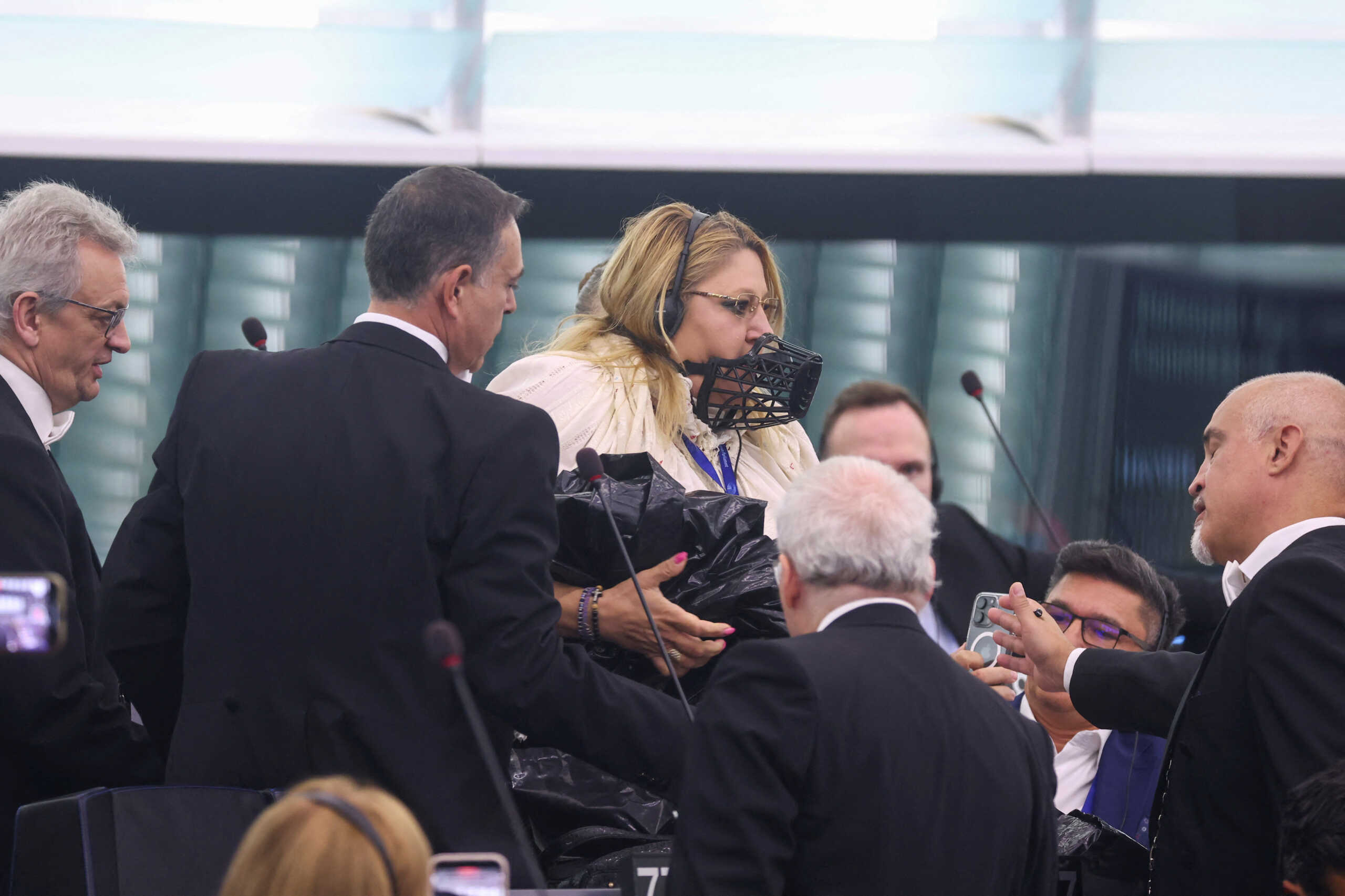 Diana Iovanovici-Sosoaca, European Parliament member and a far-right Romanian politician, wears a muzzle on her face as she is escorted out, before a vote to choose the next President of the European Commission, at the European Parliament in Strasbourg, France, July 18, 2024. REUTERS