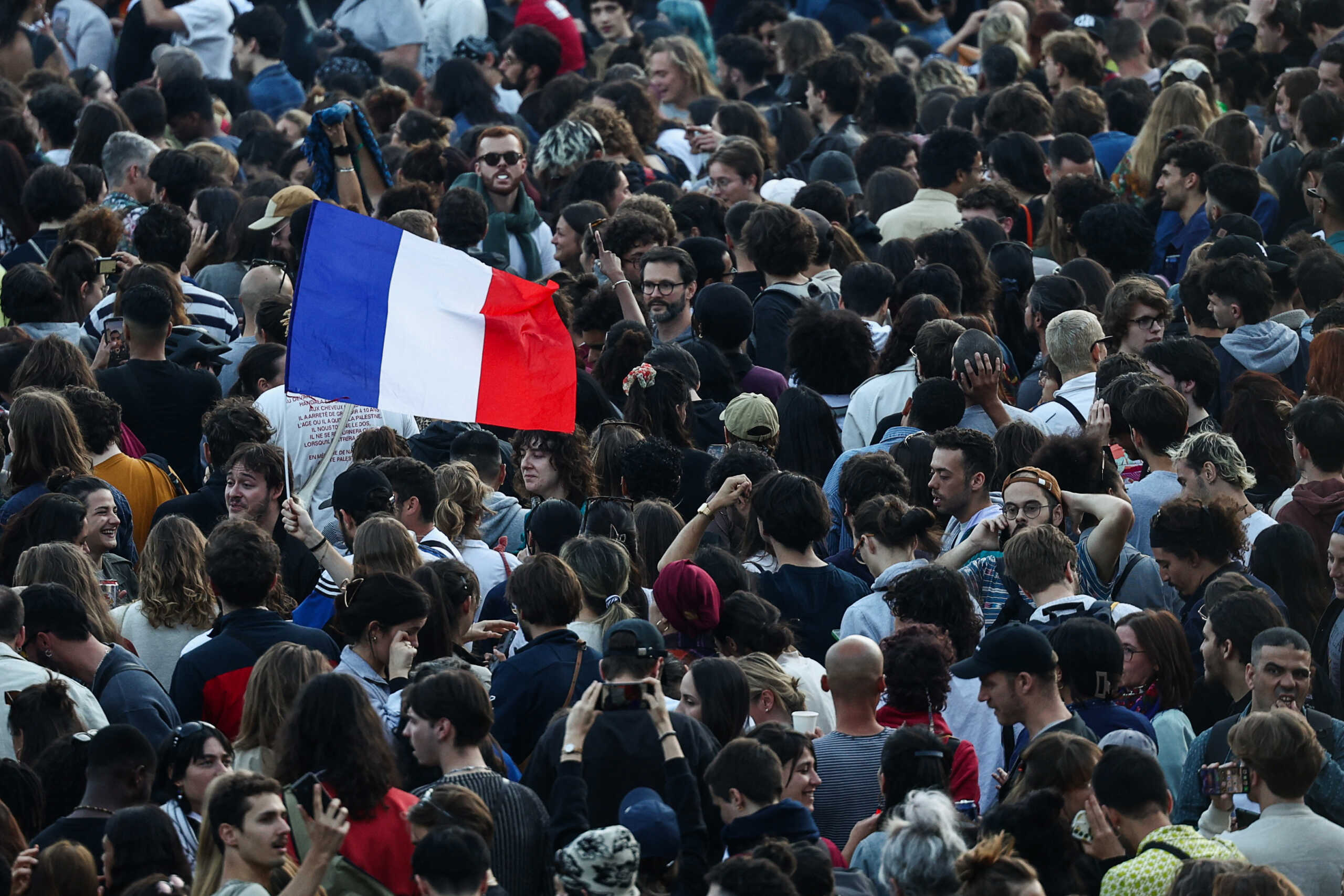 A demonstrator holds a French flag as people gather at the Place de la Republique after partial results in the second round of the early French parliamentary elections, in Paris, France, July 7, 2024. REUTERS