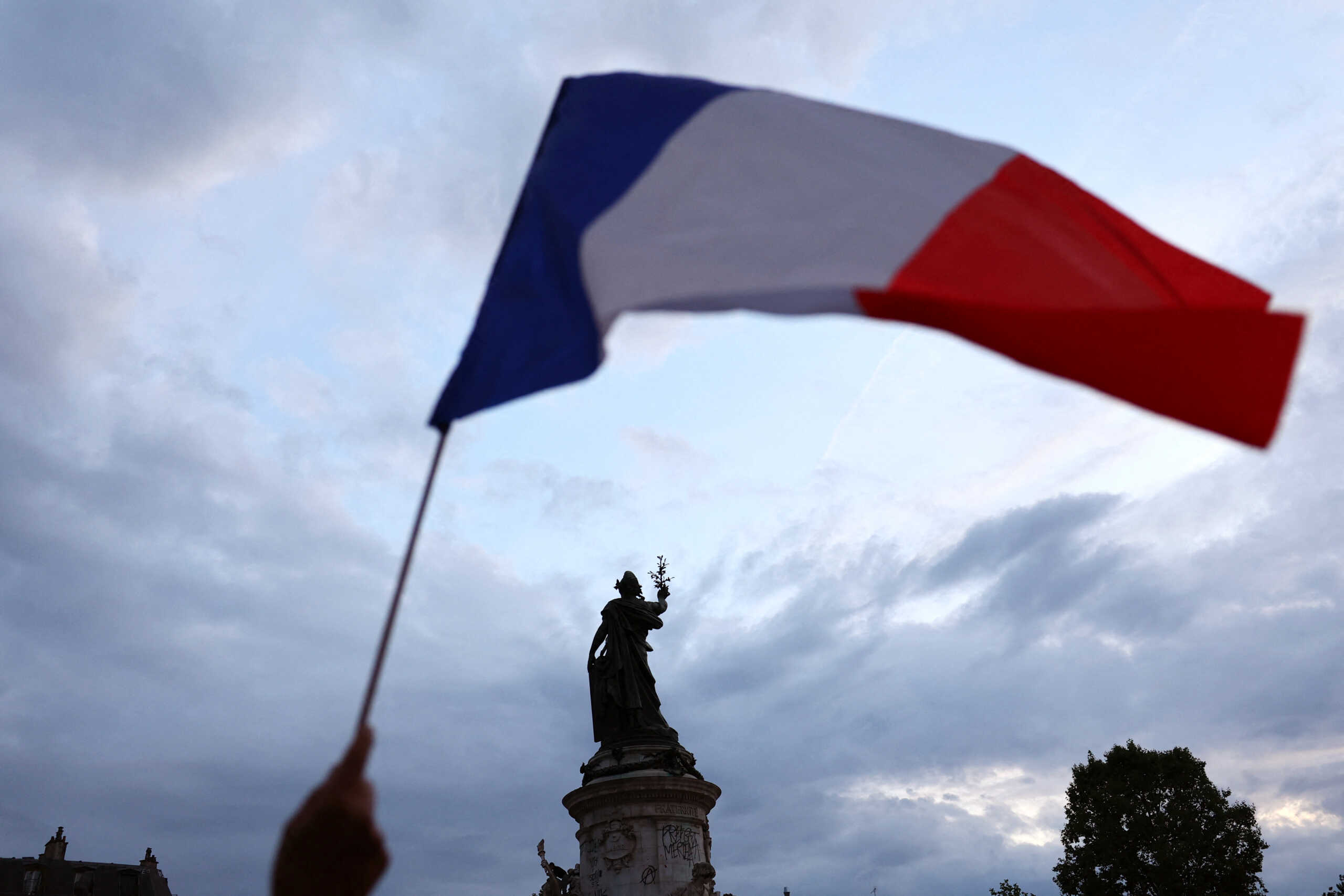A protesters holds a French national flag as people gather to protest against the French far-right Rassemblement National (National Rally - RN) party, at the Place de la Republique following partial results in the first round of the early 2024 legislative elections, in Paris, France, June 30, 2024. REUTERS