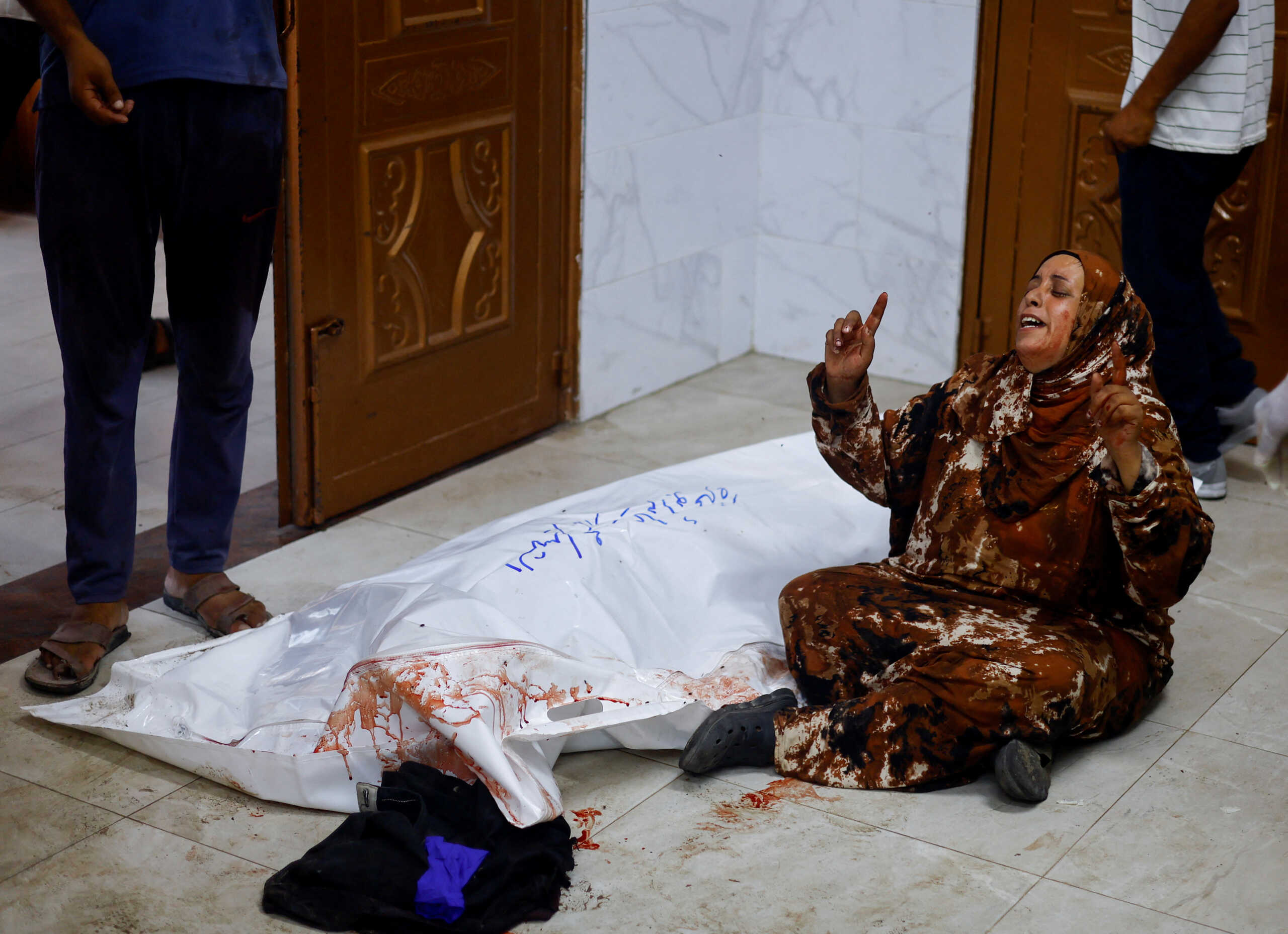 SENSITIVE MATERIAL. THIS IMAGE MAY OFFEND OR DISTURB A woman reacts next to the body of a Palestinian, following an Israeli strike, amid the Israel-Hamas conflict, at Nasser hospital in Khan Younis, in the southern Gaza Strip, July 9, 2024. REUTERS