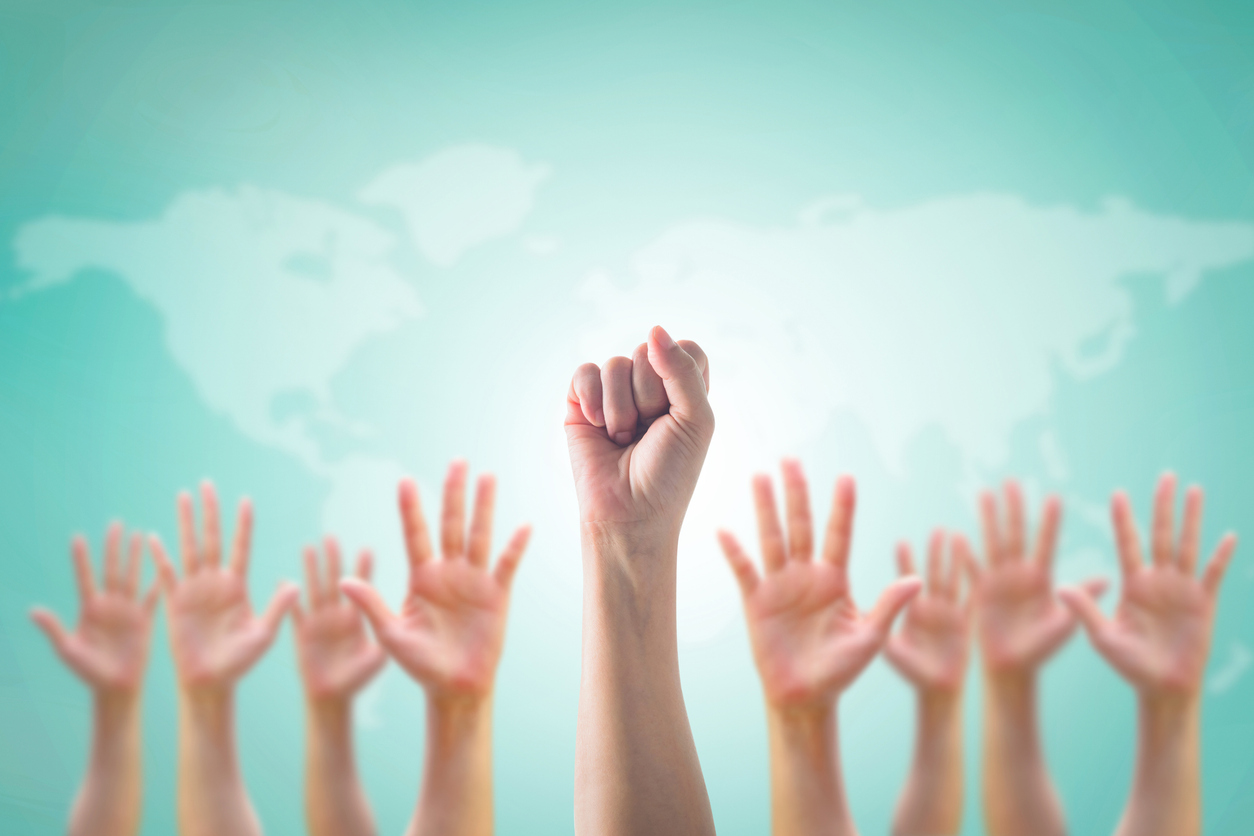 Empowering women power, human rights and labor day concept with strong fist hands on world map