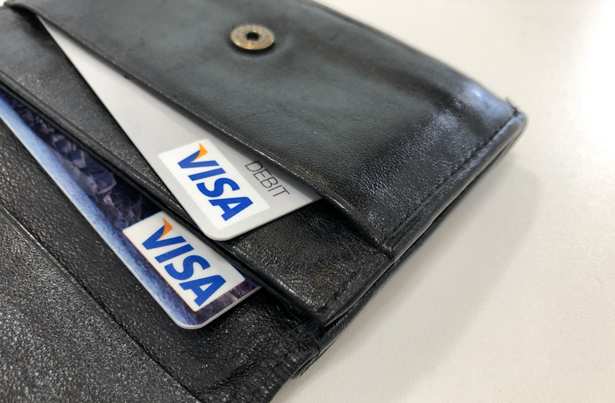 Munich, Germany Bavaria - May 22, 2021: VISA credit and debit cards in a black leather wallet with a white table surface background.
