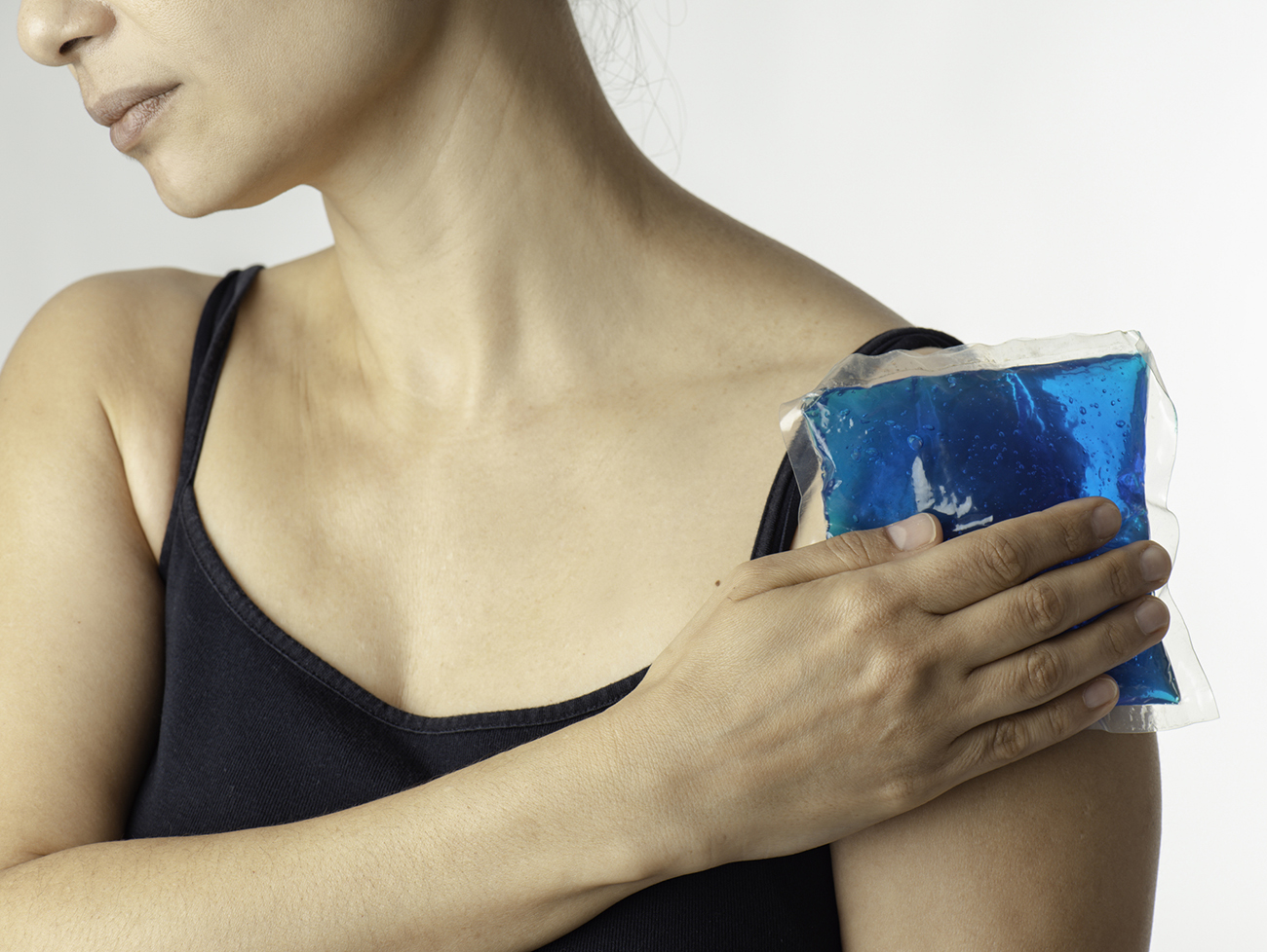 Shot of a young woman holding an icepack on her shoulder to ease the pain.