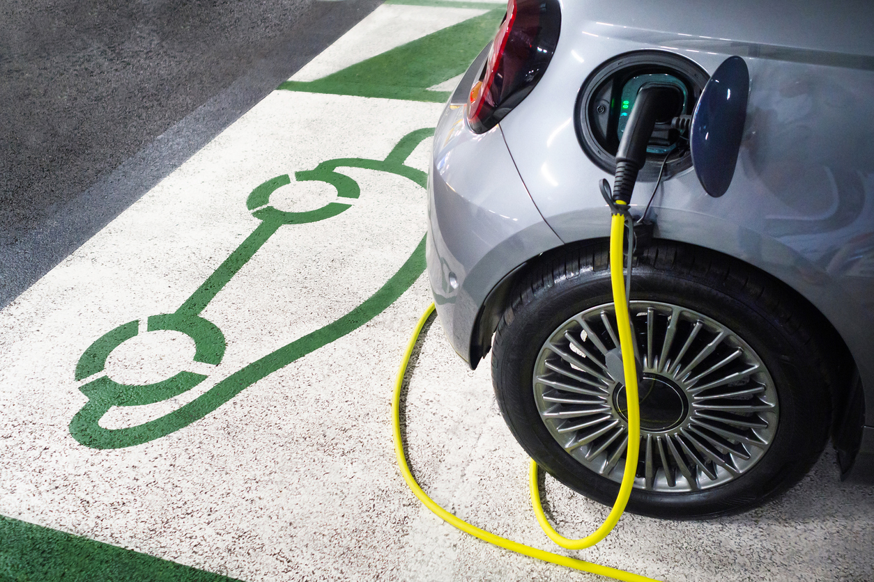 Electric car charging at parking charging station.