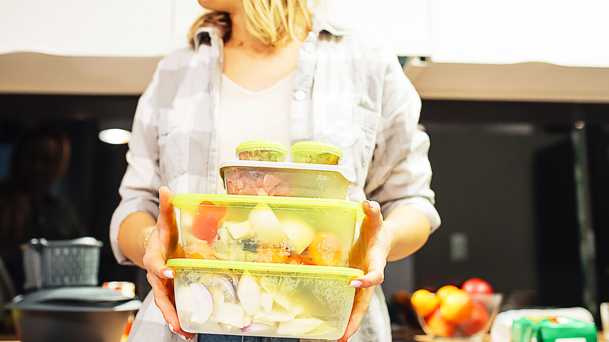 Hands of woman hold plastic containers with different frozen foodstuffs. Cooking dinner at home kitchen. Hermetically sealed food storage. Homemade dish, recipe, food ingredients and tableware.