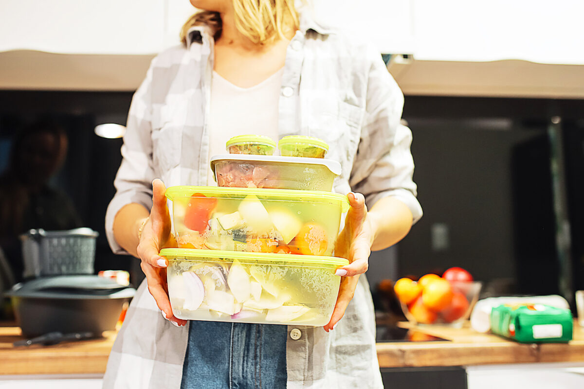 Hands of woman hold plastic containers with different frozen foodstuffs. Cooking dinner at home kitchen. Hermetically sealed food storage. Homemade dish, recipe, food ingredients and tableware.
