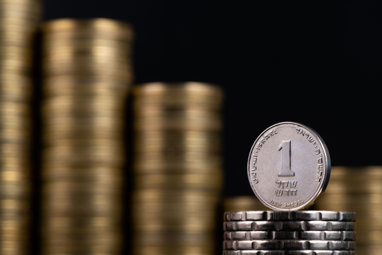 1 Israeli shekel coin on the background of a stack of gold coins