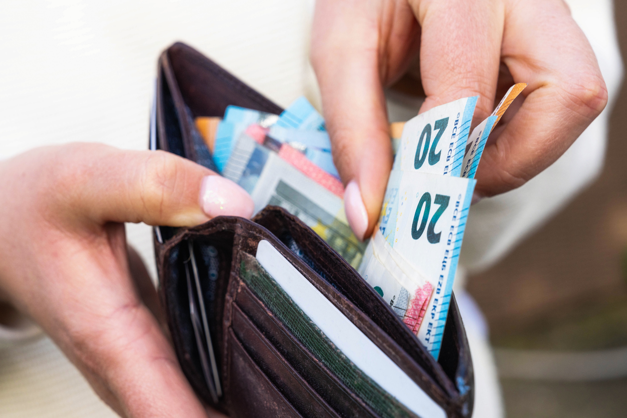 Macro image as a woman takes Euro banknotes from a leather wallet.