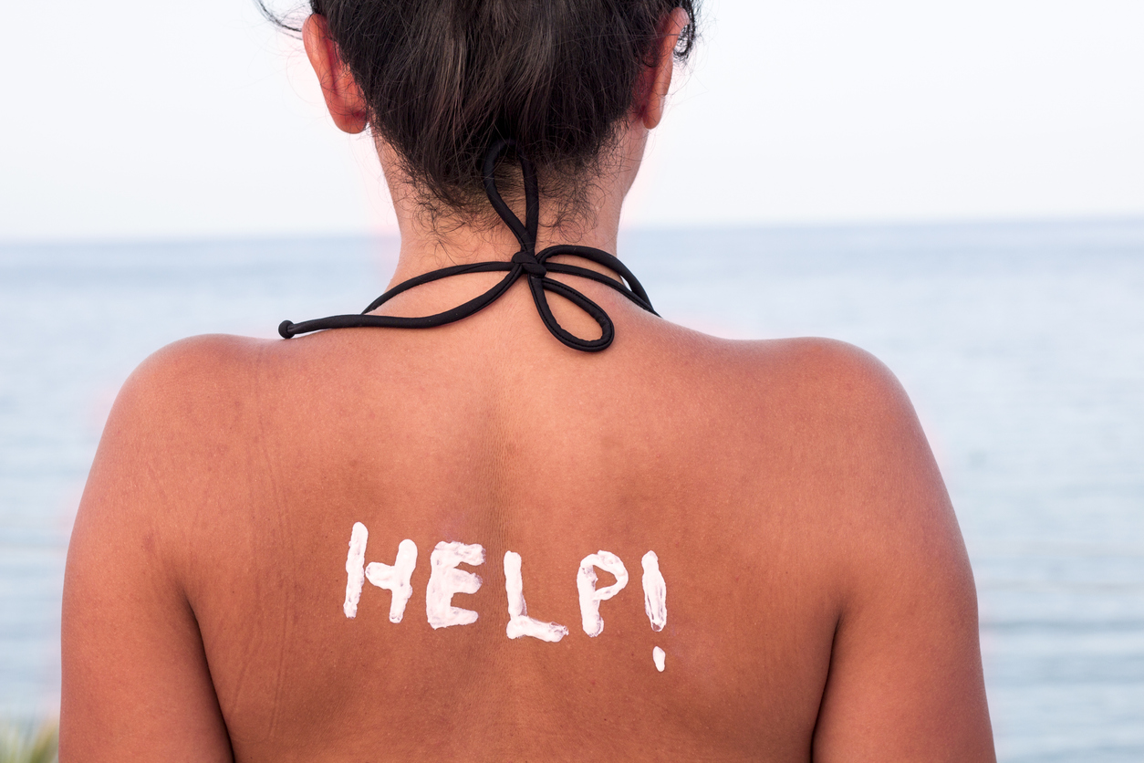 Help written with sun cream on a woman's shoulder, horizontal