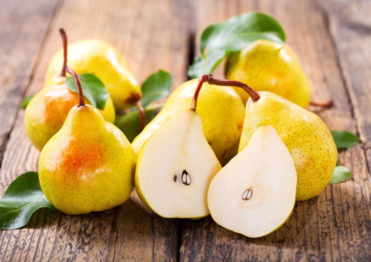 fresh pears with leaves on wooden table