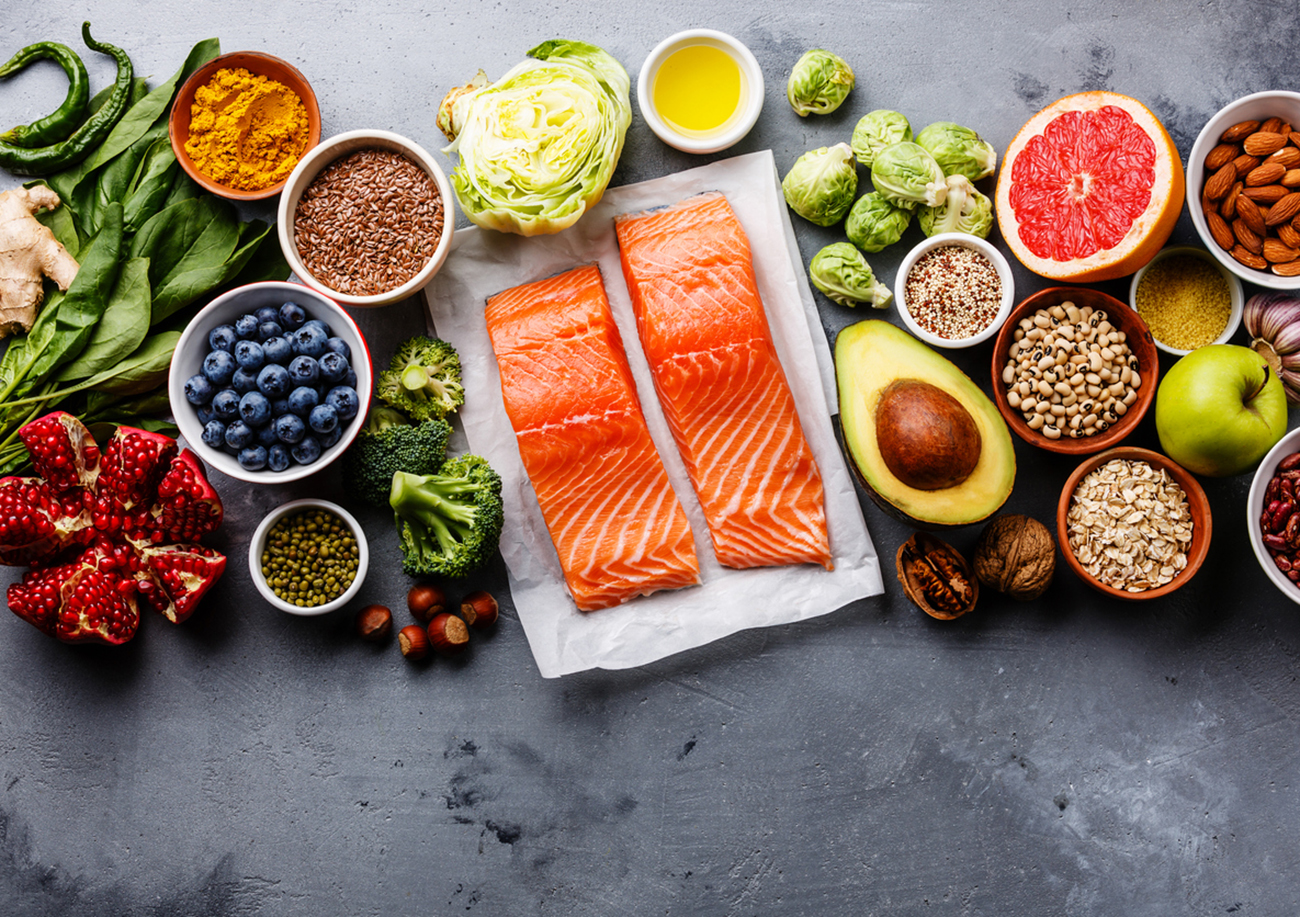 Healthy food clean eating selection: fish, fruit, vegetable, seeds, superfood, cereals, leaf vegetable on gray concrete background copy space