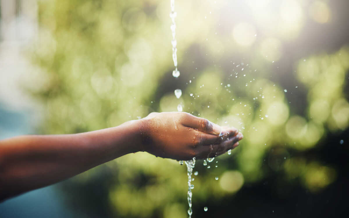 Cropped shot of hands held out to catch a stream of water outside
