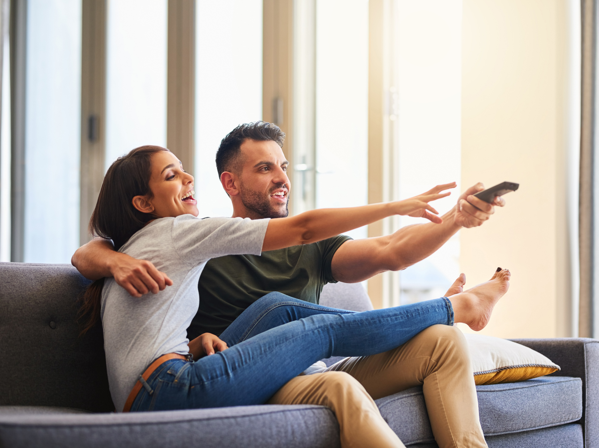 Shot of a young couple fighting over the remote control while watching tv at home