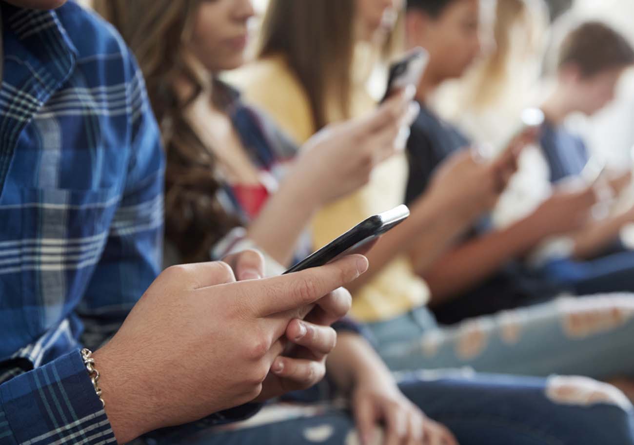 Close Up Of A Line Of High School Students Using Mobile Phones