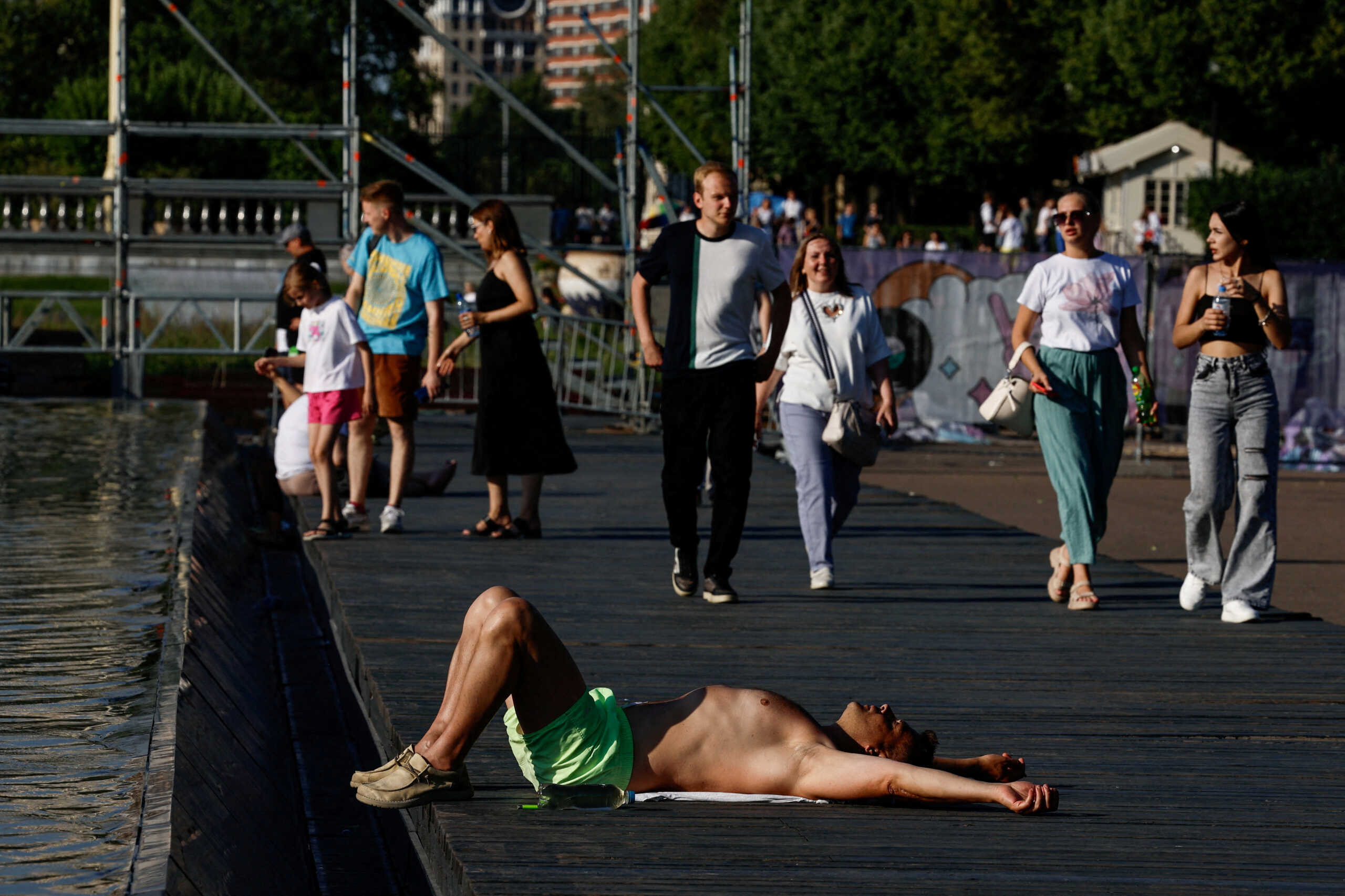 FILE PHOTO: A man lies near a fountain in a park during hot weather in Moscow, Russia July 2, 2024.  REUTERS
