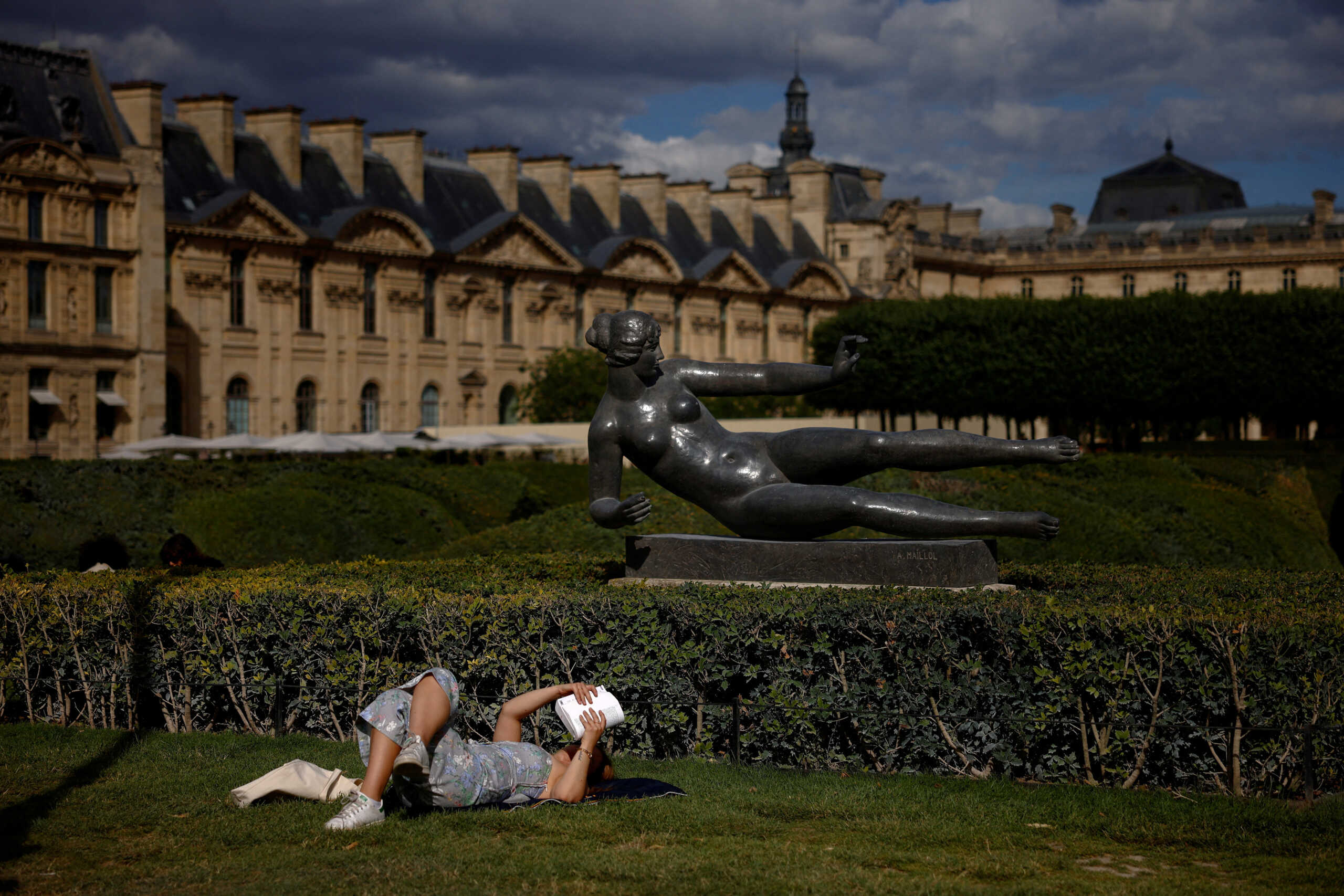 A woman reads a book as she sits on the grass in the Tuileries Garden, one day before the second round of early French parliamentary elections in Paris, France, July 6, 2024. REUTERS