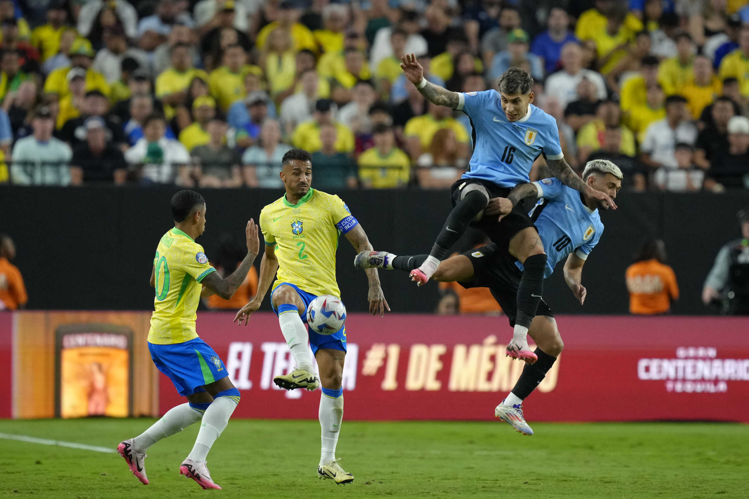 Jul 6, 2024; Las Vegas, NV, USA; Brazil defender Danilo (2) kicks the ball against Uruguay defender Mathias Olivera (16) and midfielder Giorgian de Arrascaeta (10) during the second half at Allegiant Stadium. Mandatory Credit: Lucas Peltier-USA TODAY Sports