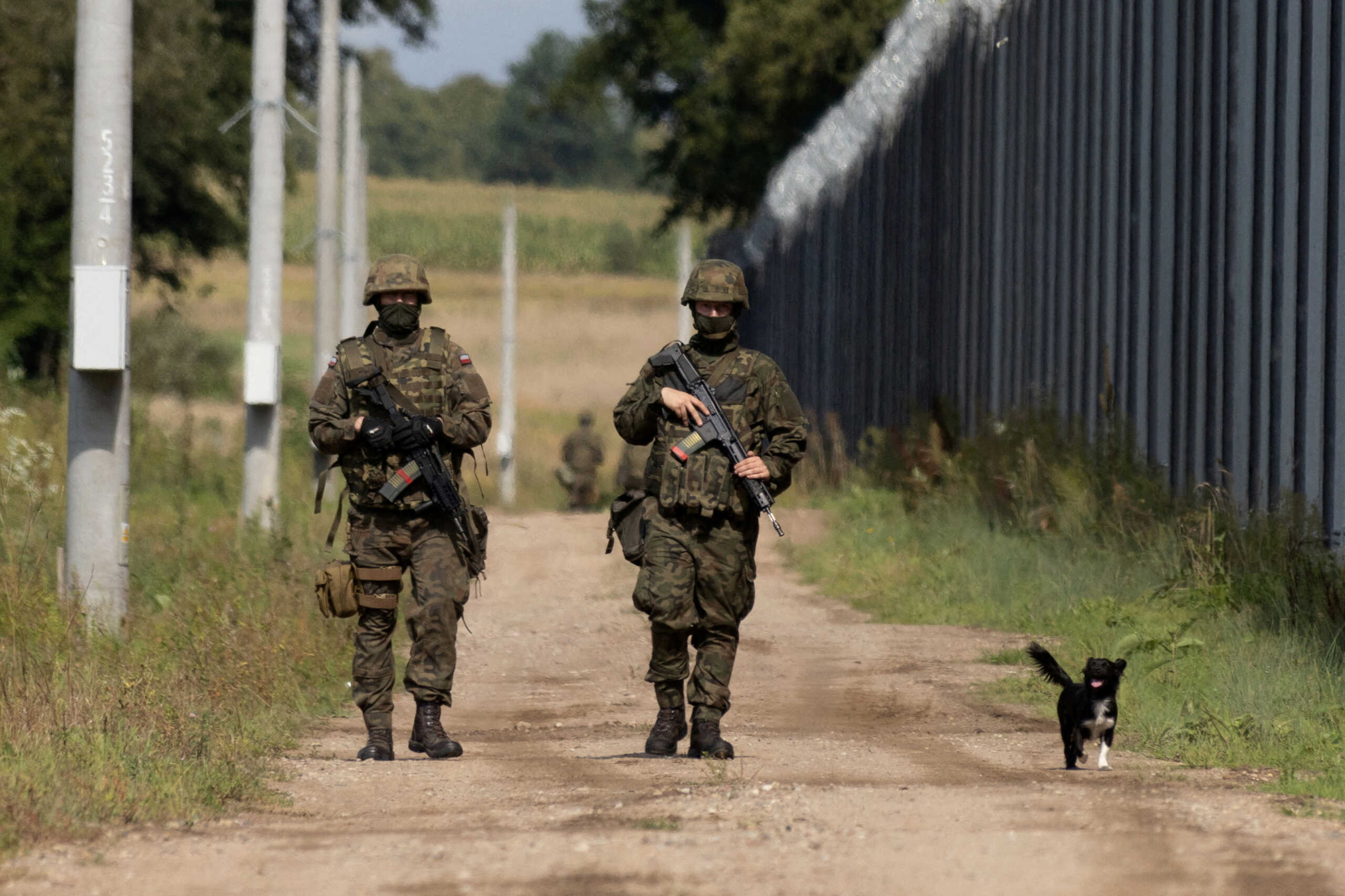 FILE PHOTO: Polish soldiers and a local dog walk along the border fence on the Polish-Belarusian border in Usnarz Gorny, Poland, August 30, 2023. REUTERS