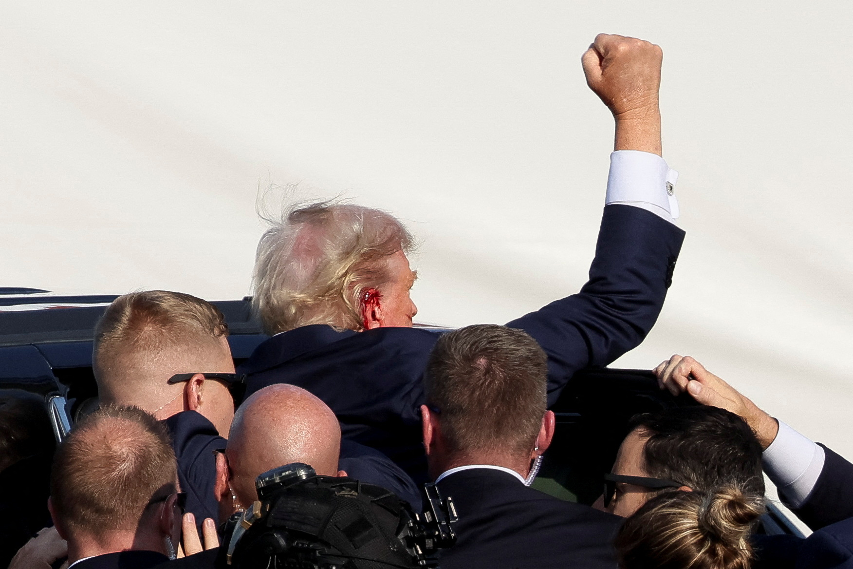 Republican presidential candidate and former U.S. President Donald Trump gestures as he is assisted by security personnel after gunfire rang out during a campaign rally at the Butler Farm Show in Butler, Pennsylvania, U.S., July 13, 2024. REUTERS