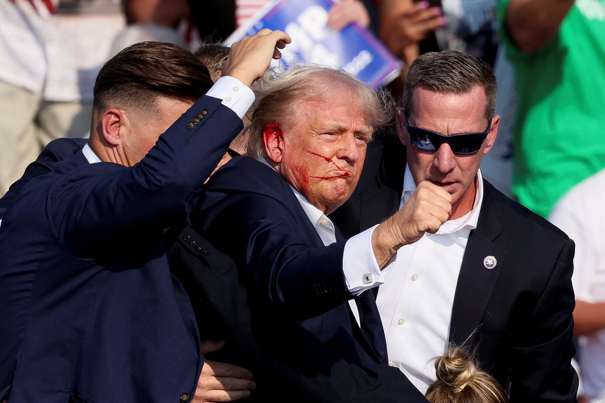 Republican presidential candidate and former U.S. President Donald Trump gestures as he is assisted by security personnel after gunfire rang out during a campaign rally at the Butler Farm Show in Butler, Pennsylvania, U.S., July 13, 2024. REUTERS