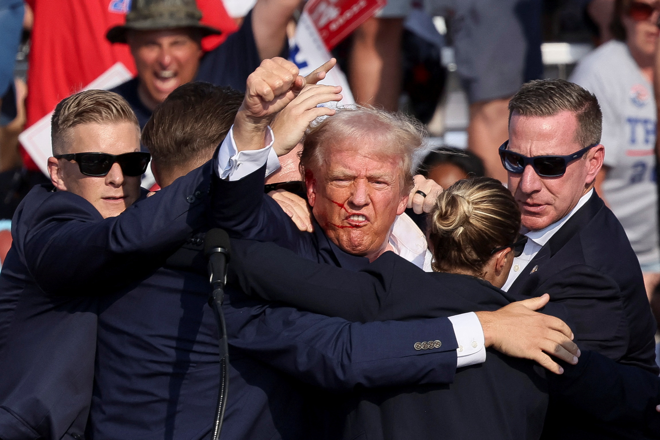 Republican presidential candidate and former U.S. President Donald Trump is assisted by security personnel after gunfire rang out during a campaign rally at the Butler Farm Show in Butler, Pennsylvania, U.S., July 13, 2024. REUTERS