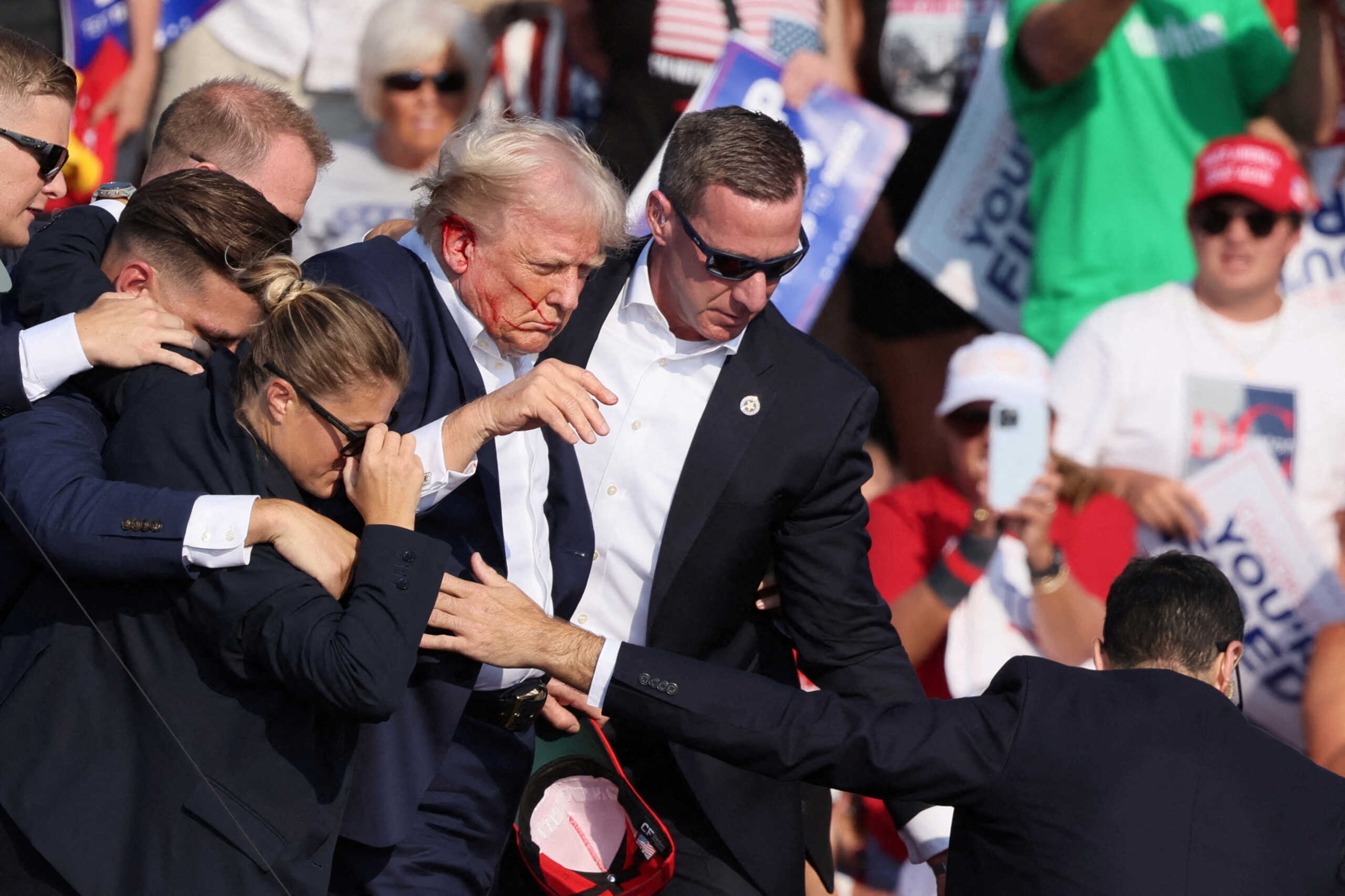 Republican presidential candidate and former U.S. President Donald Trump with his bloodied face is assisted by the Secret Service as multiple shots rang out during a campaign rally at the Butler Farm Show in Butler, Pennsylvania, U.S., July 13, 2024. REUTERS
