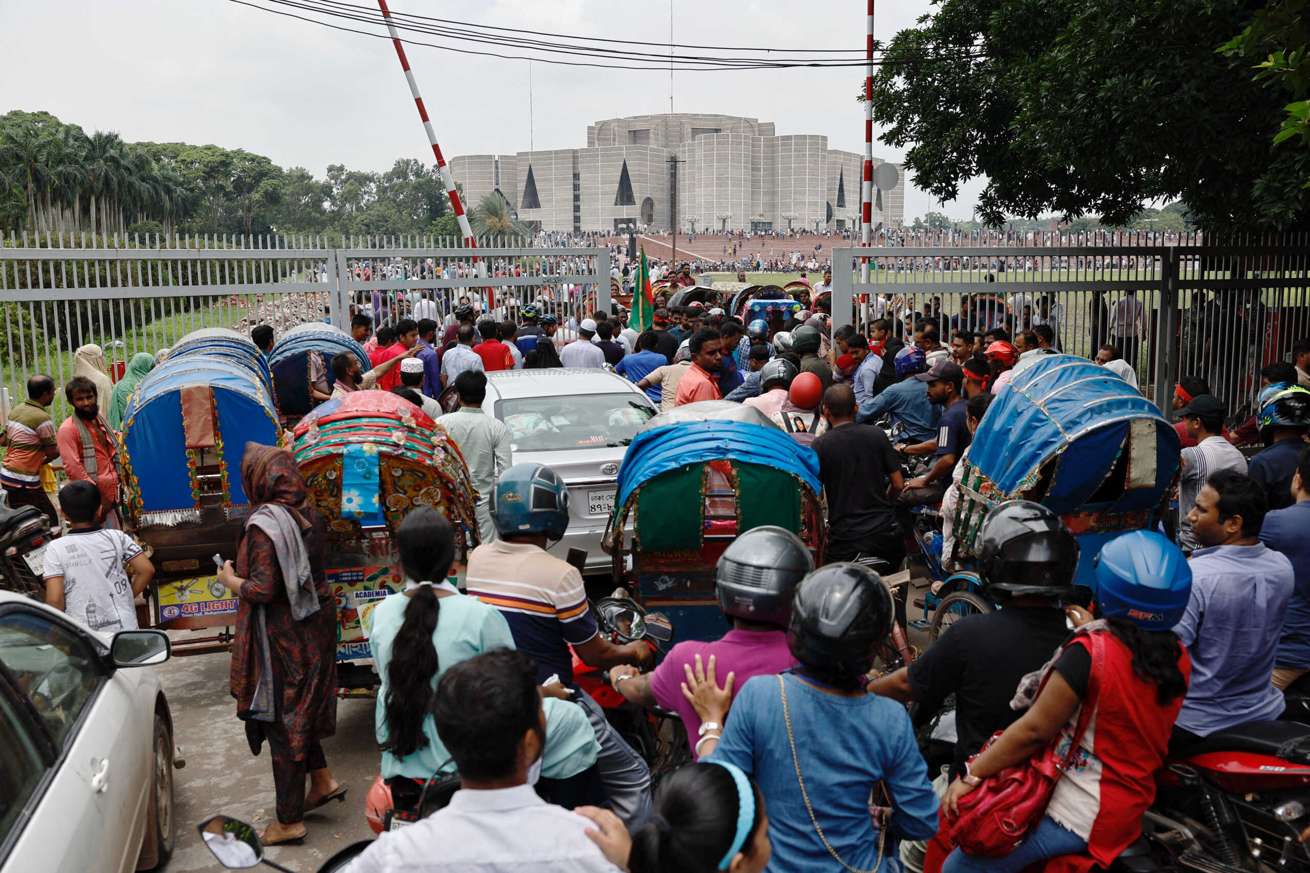 People and vehicles cram at the gate as they gather outside the parliament building, a day after the resignation of Bangladeshi Prime Minister Sheikh Hasina, in Dhaka, Bangladesh, August 6, 2024. REUTERS