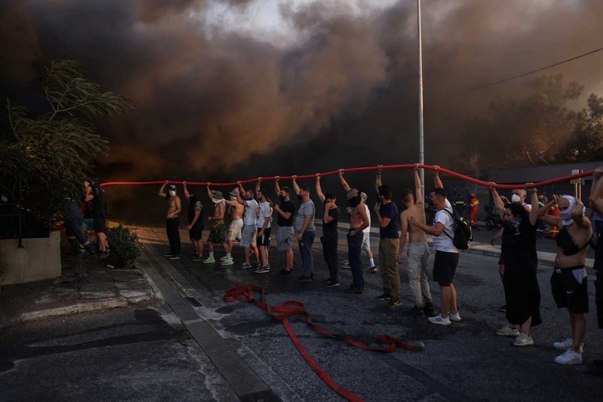 Volunteers and firefighters try to extinguish a fire in a building as a wildfire burns in Vrilissia near Athens, Greece, August 12, 2024. REUTERS