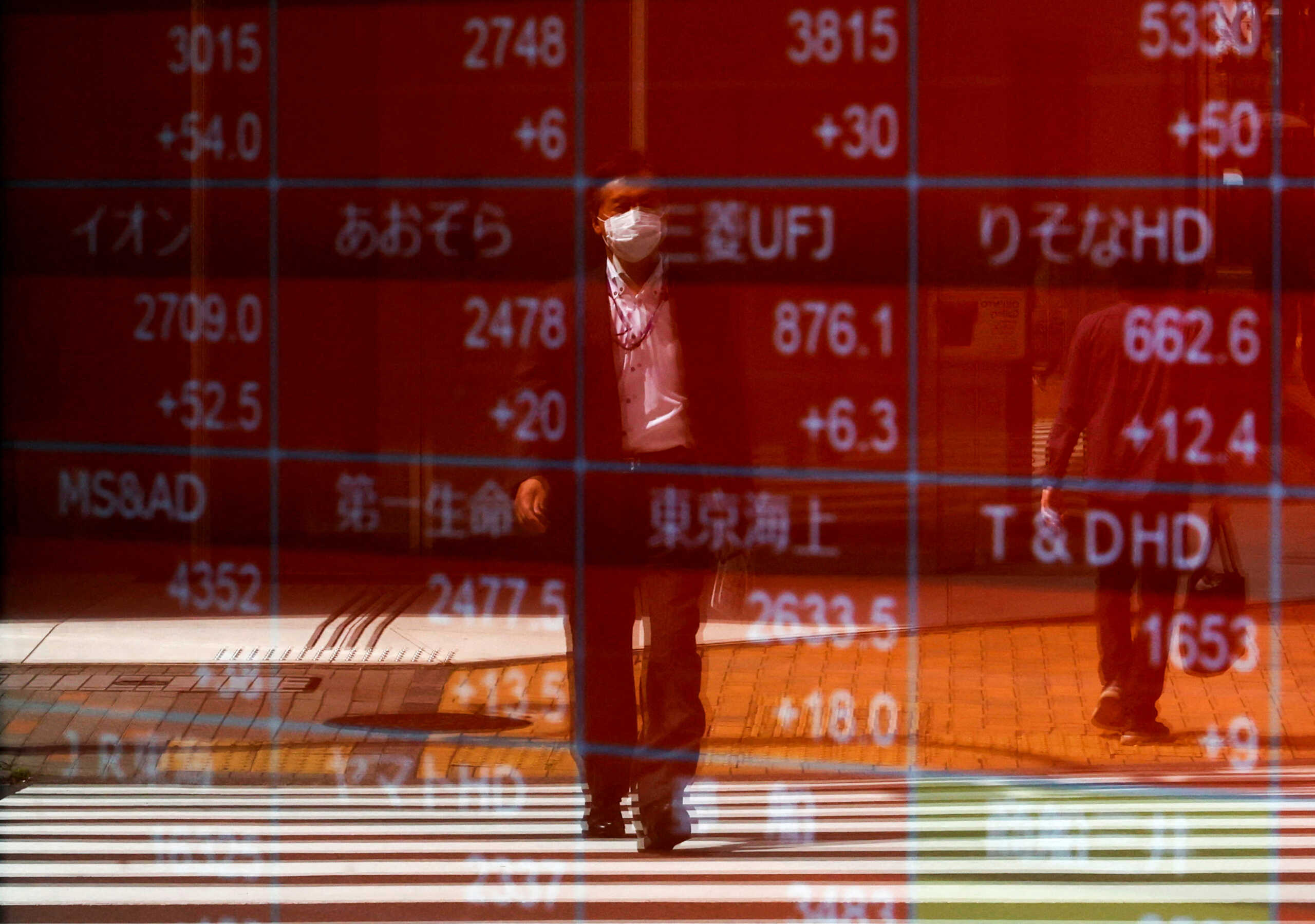 FILE PHOTO: A man is reflected on an electric stock quotation board outside a brokerage in Tokyo, Japan April 18, 2023.  REUTERS