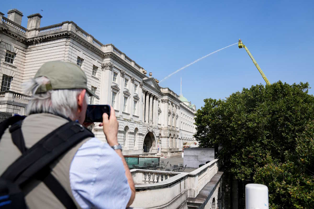 A man records images as firefighters work at the scene of a fire at Somerset House in London, Britain August 17, 2024. REUTERS