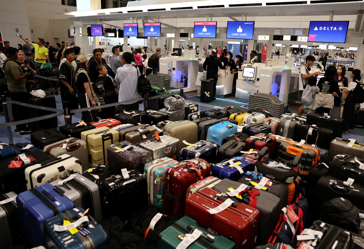 FILE PHOTO: Passengers stands in a line at Delta Airlines’ counter following a global IT outage, at Haneda International Airport in Tokyo, Japan July 19,  2024. REUTERS