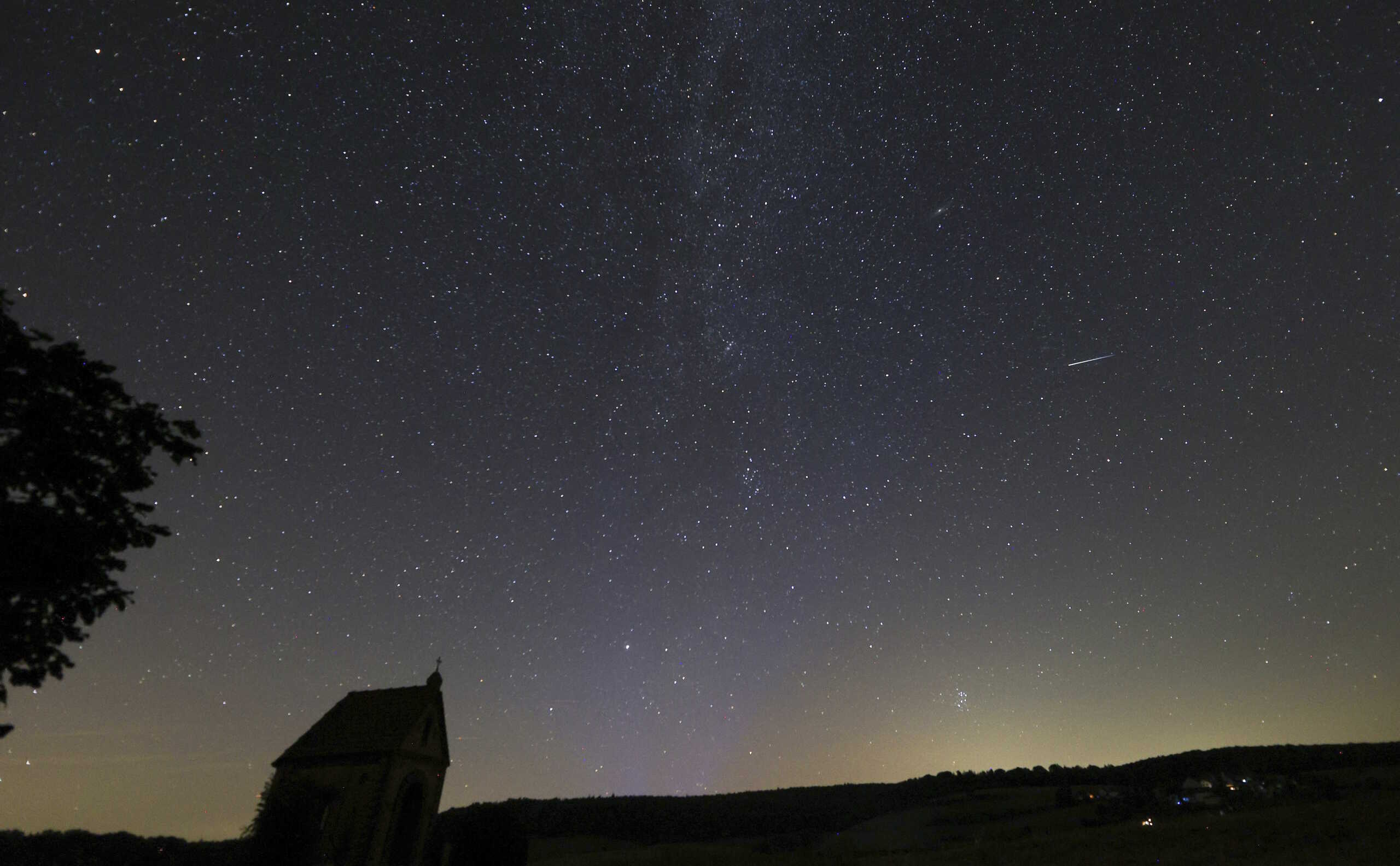 11 August 2024, Baden-W'rttemberg, Zwiefalten: A shooting star of the Perseids can be seen in the sky near M'rsingen on the Swabian Alb next to the Milky Way. Photo by: Thomas Warnack