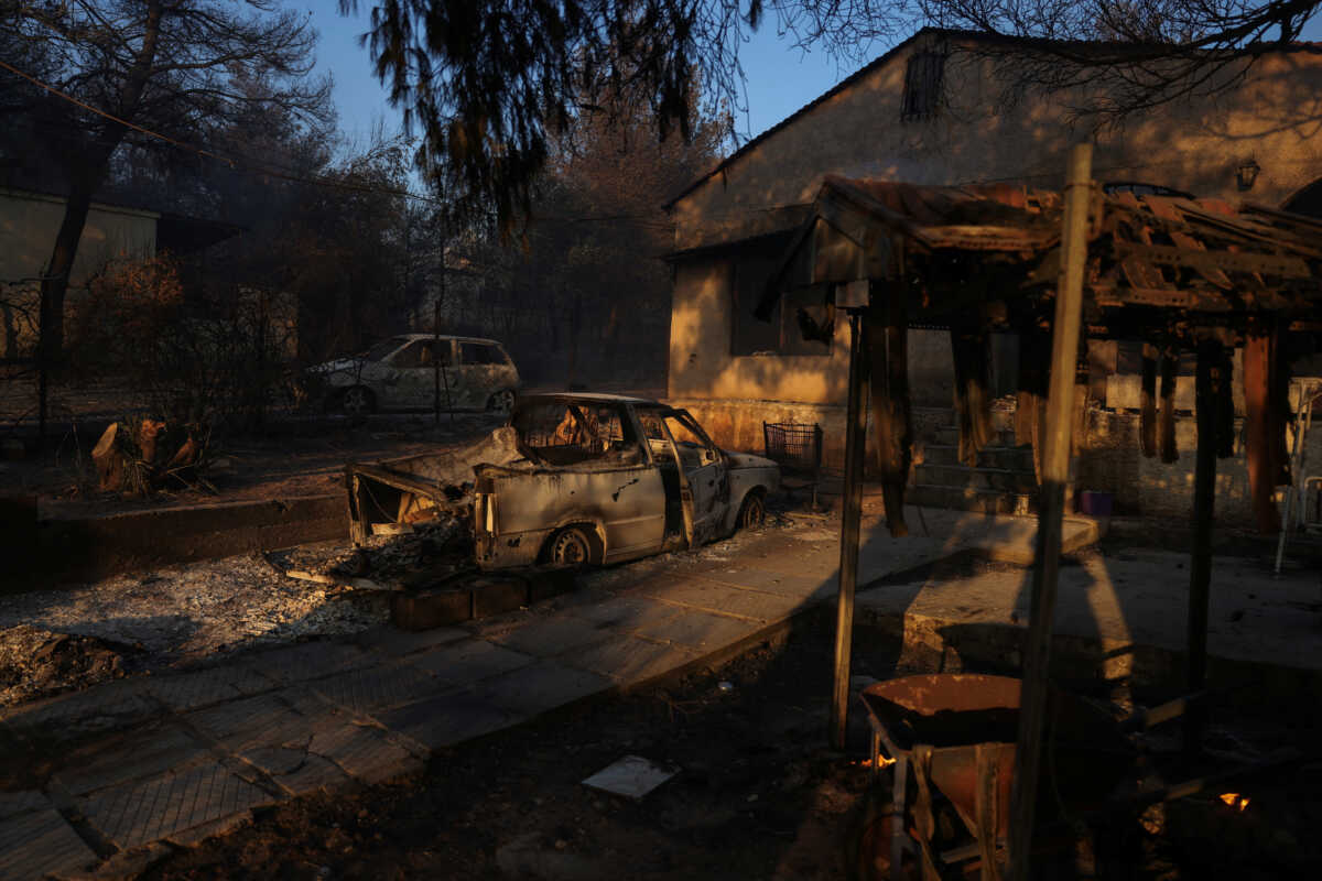 A damaged house and a destroyed car are seen, as a wildfire burns in Vrilissia near Athens, Greece, August 12, 2024. REUTERS