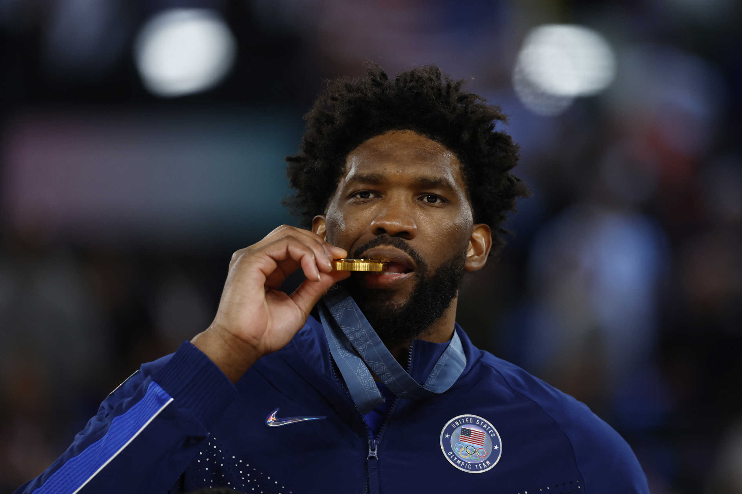 Paris 2024 Olympics - Basketball - Men's Victory Ceremony - Bercy Arena, Paris, France - August 10, 2024. Gold medallist Joel Embiid of United States bites his medal. REUTERS