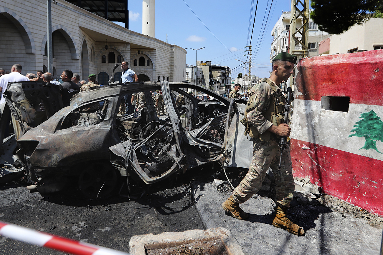 A Lebanese army soldier passes in front a car that was hit by an Israeli strike in the southern port city of Sidon, Lebanon, Wednesday, Aug. 21, 2024. (AP Photo