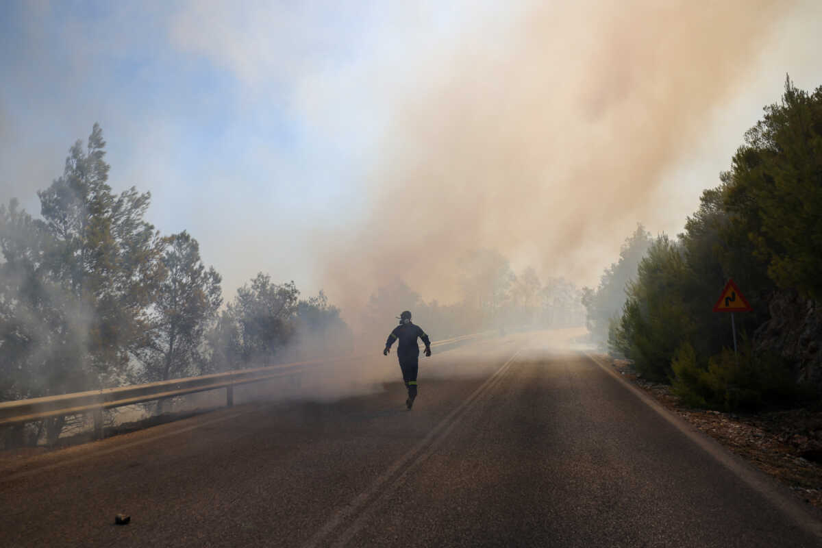 A firefighter runs as a wildfire burns in Penteli, Greece, August 12, 2024. REUTERS